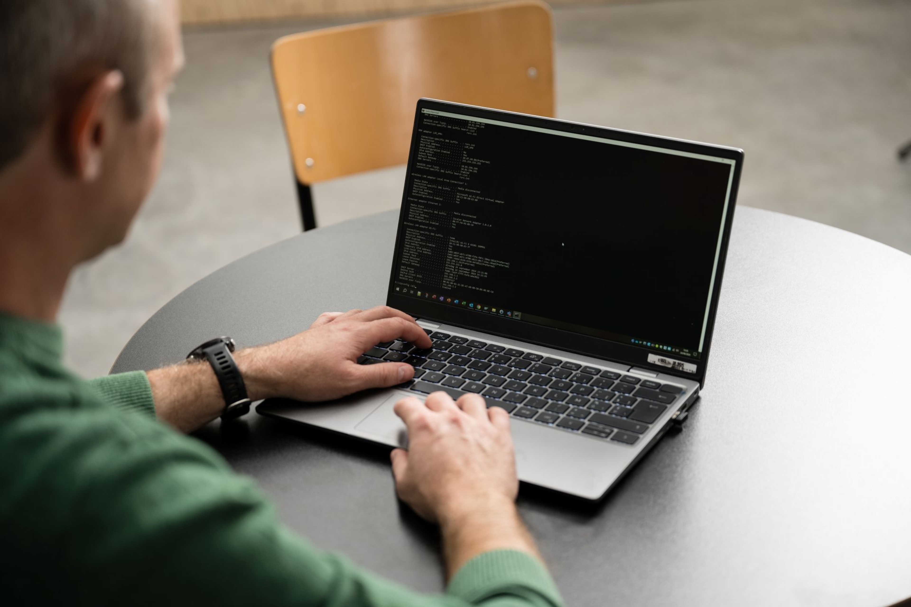 Jonge man met groene trui achter een laptop.