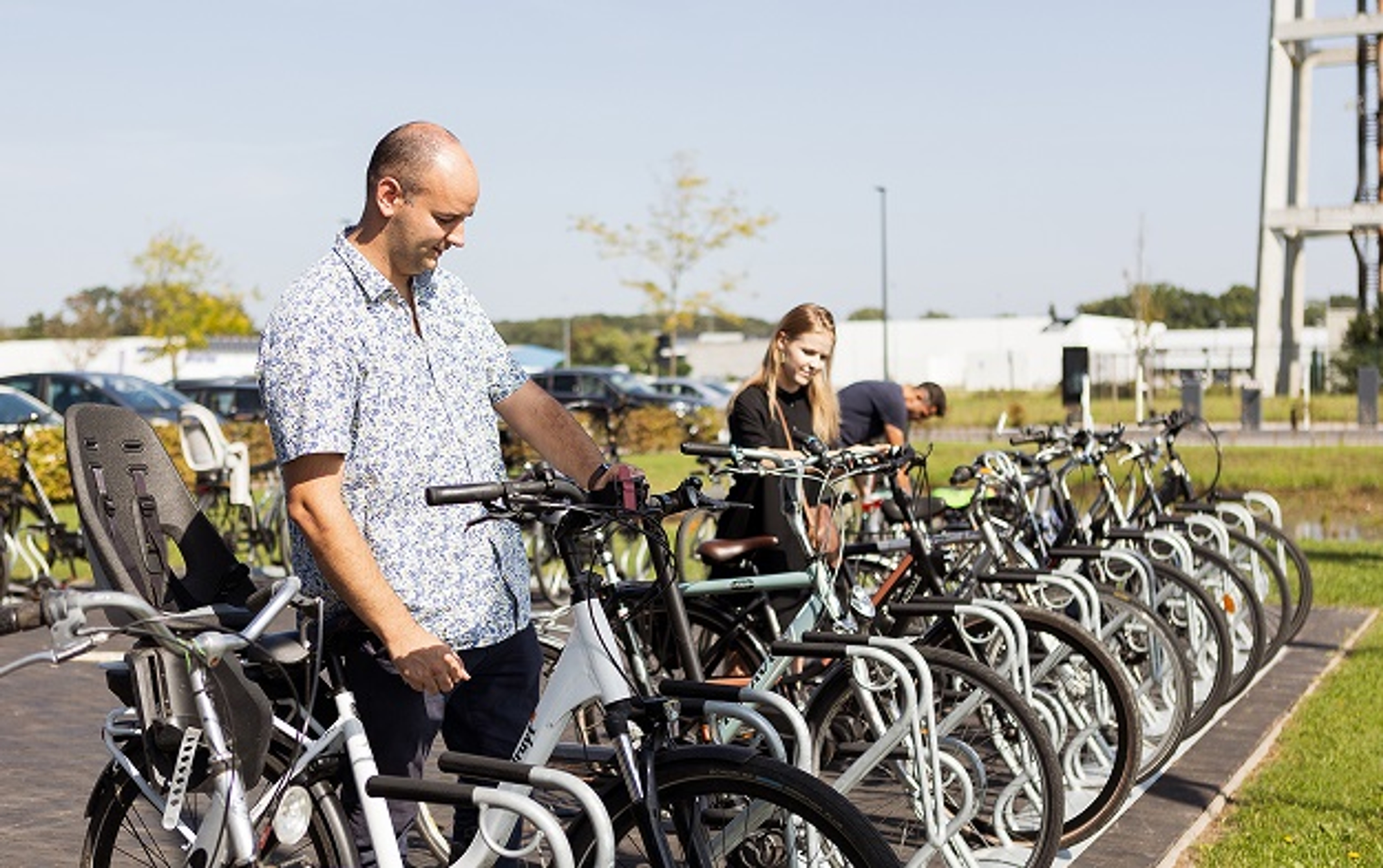 Luminus fietsparking Corda Campus: 2 mannen en 1 dame maken hun fiets vast.