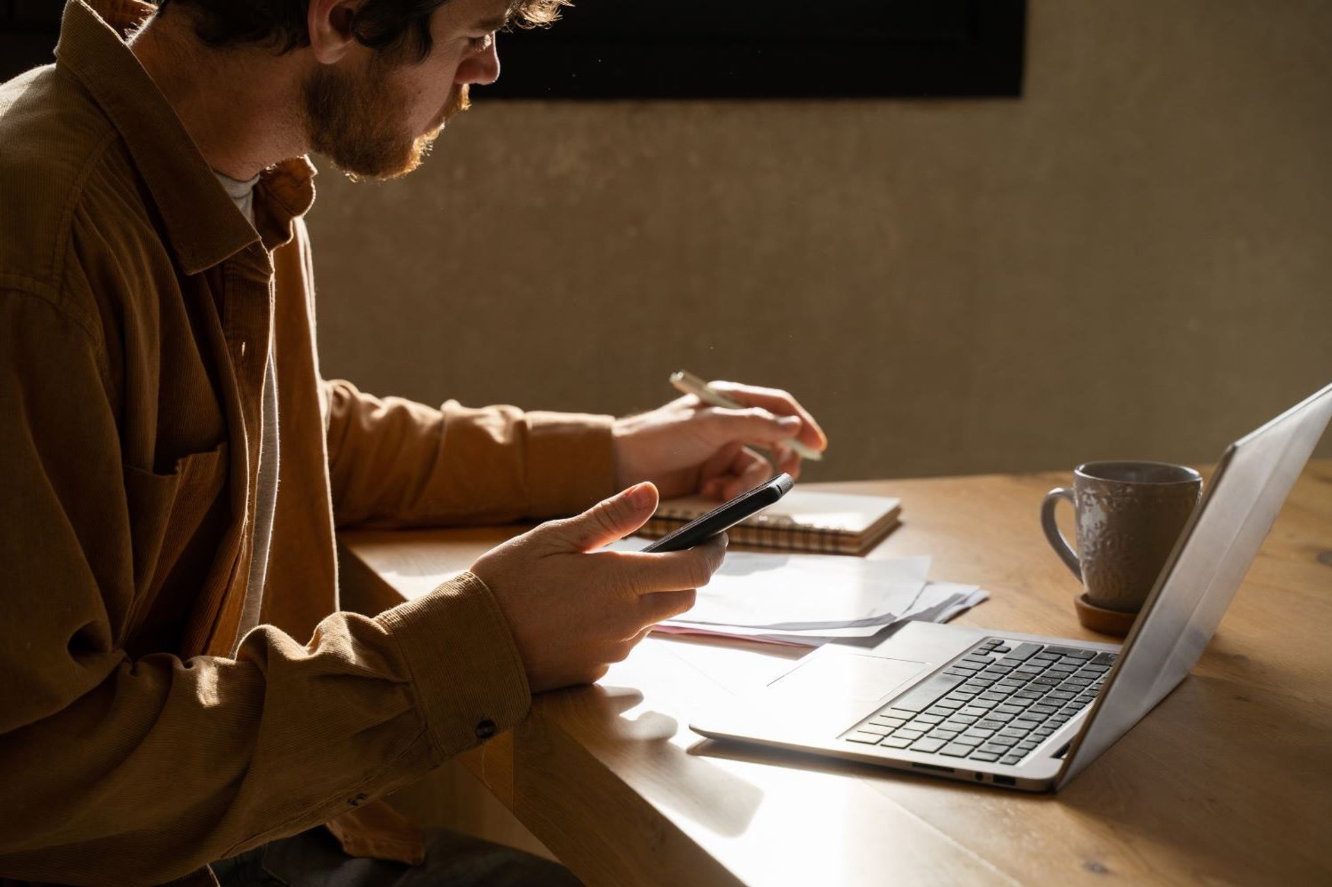 Jonge man aan tafel met laptop en gsm