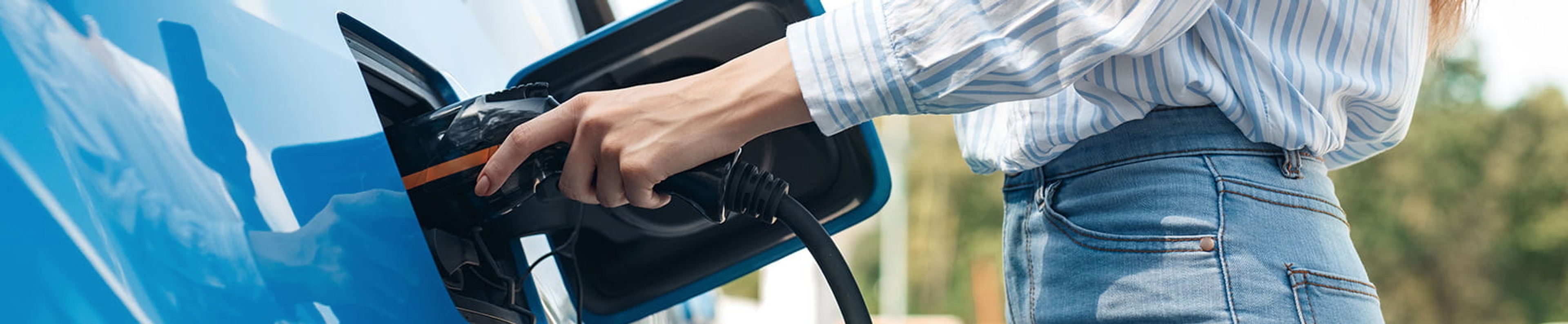 Close-up van dame die de stekker in haar elektrische wagen steekt.