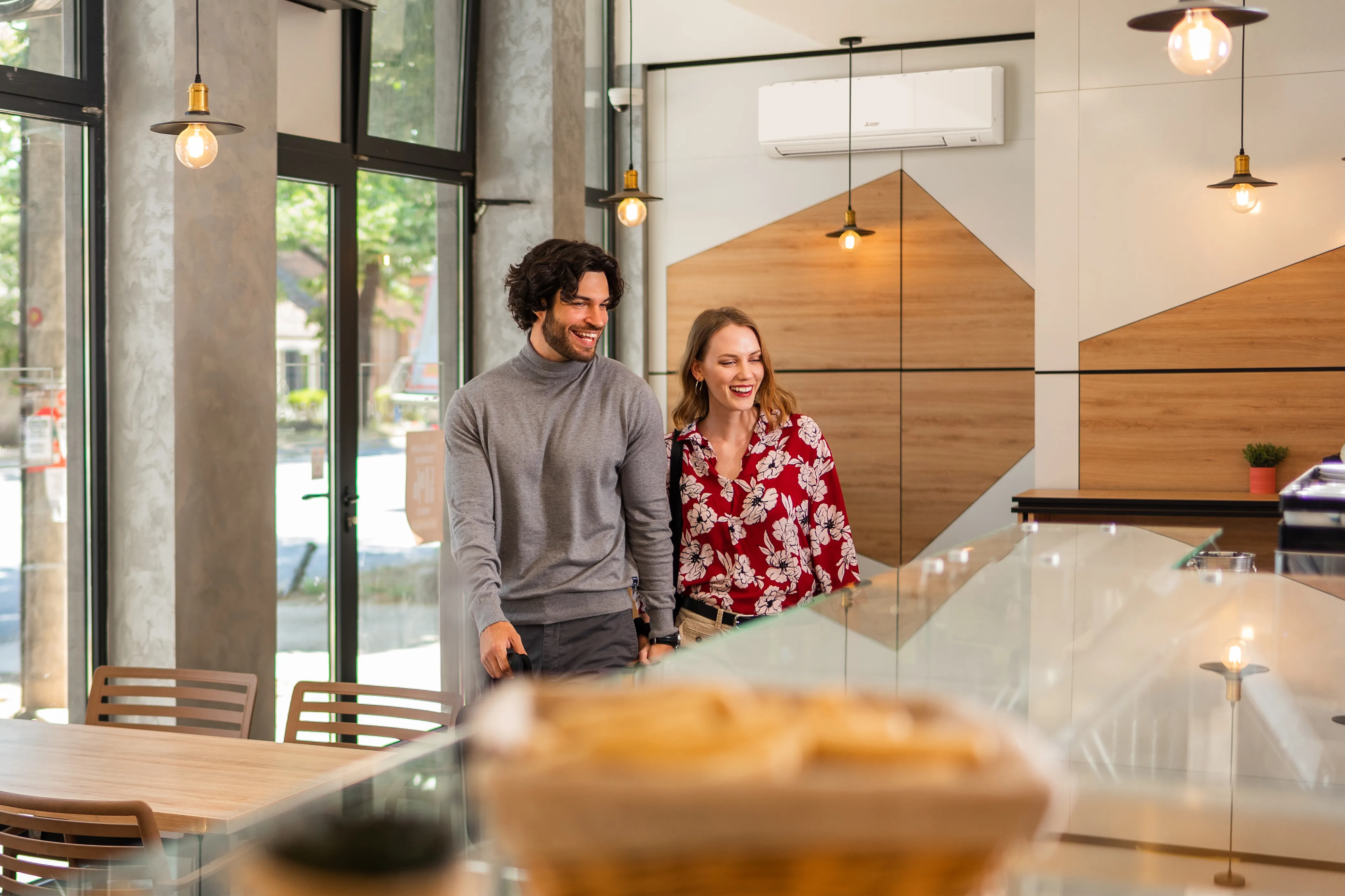 Vrolijk koppel in een moderne snackbar, aan de muur hangt een warmtepomp. 