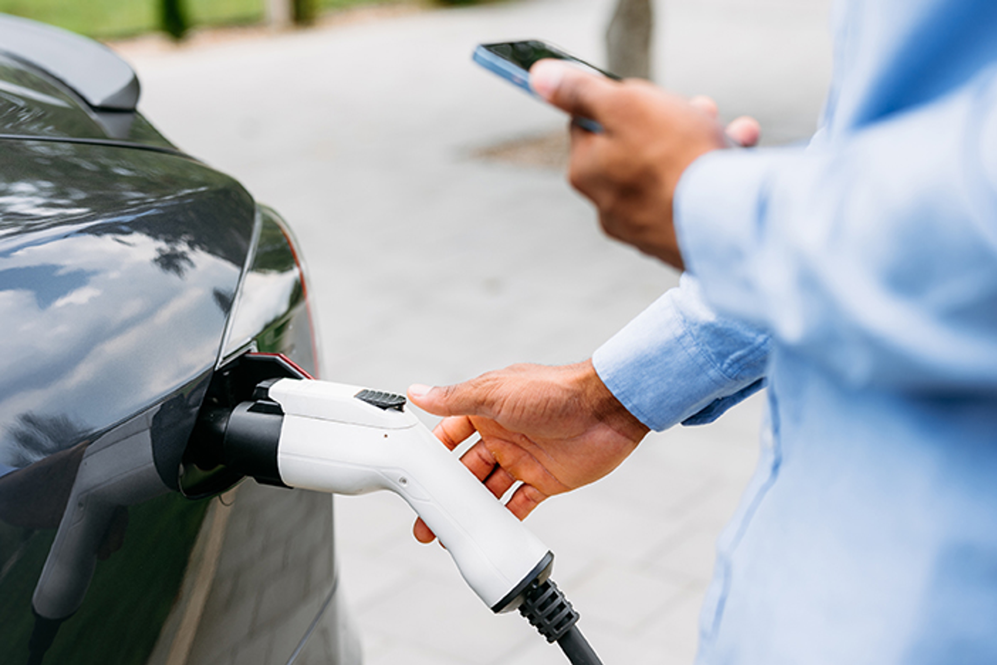 Recharge de voiture : une main insère le chargeur dans la prise d’un véhicule