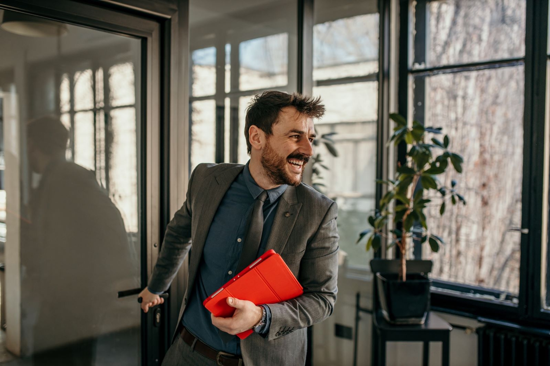 Homme entrant dans un bureau en souriant avec un dossier en main