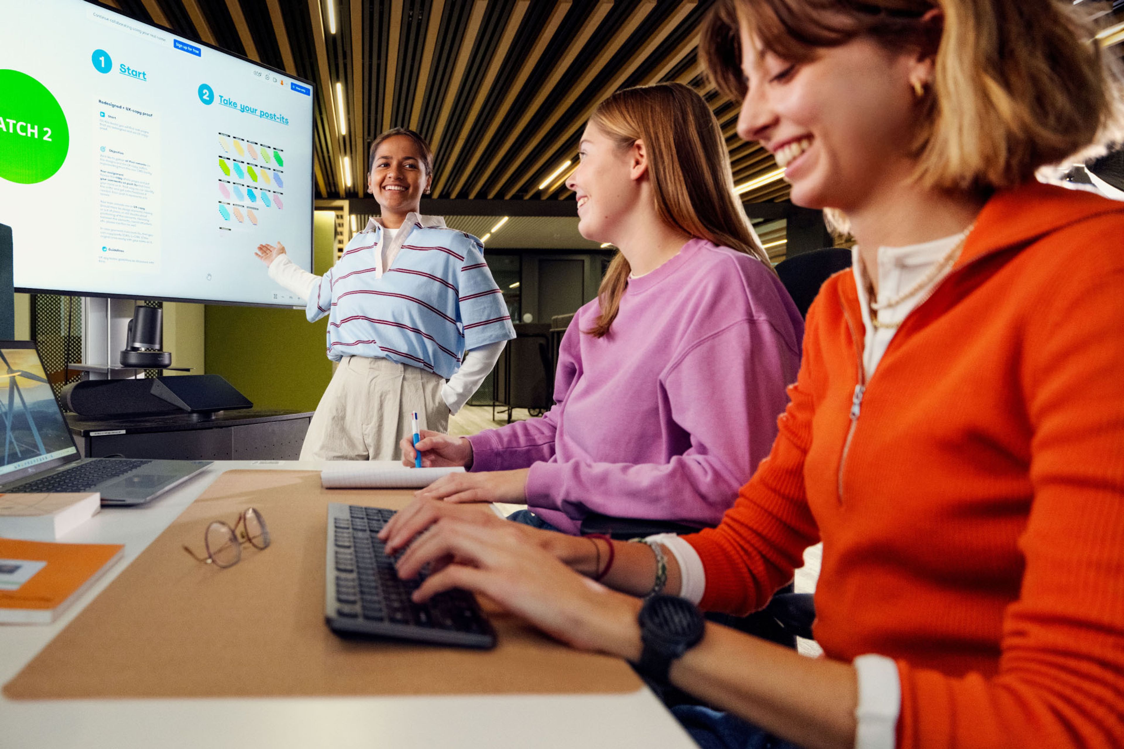 Luminus Young IT Track: 3 jongedames op kantoor, eentje toont iets op het projectiescherm.