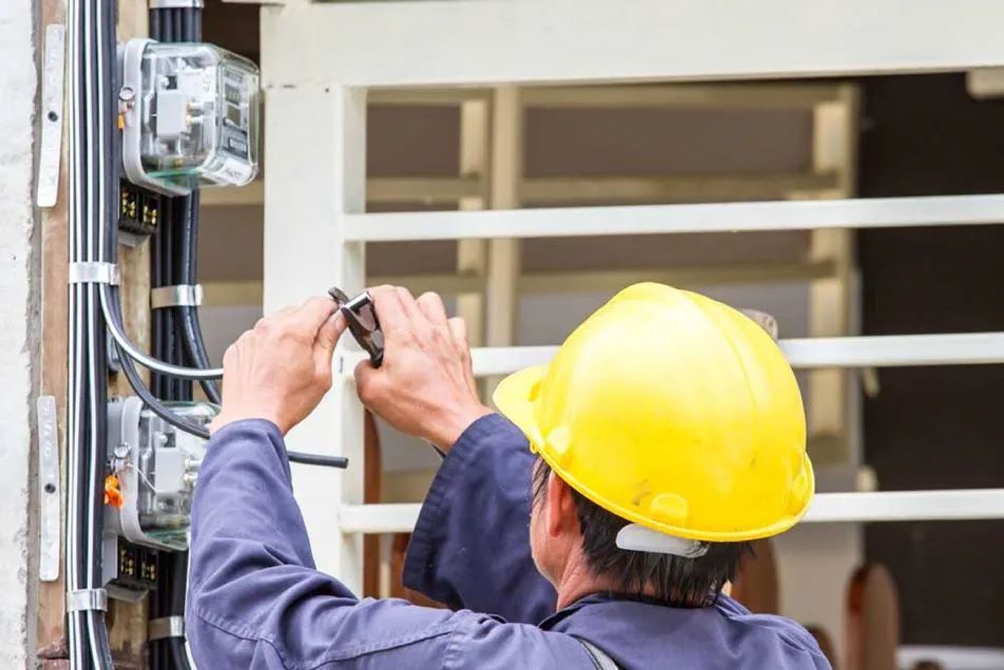 Technieker met gele helm knipt elektriciteitsdraad door.