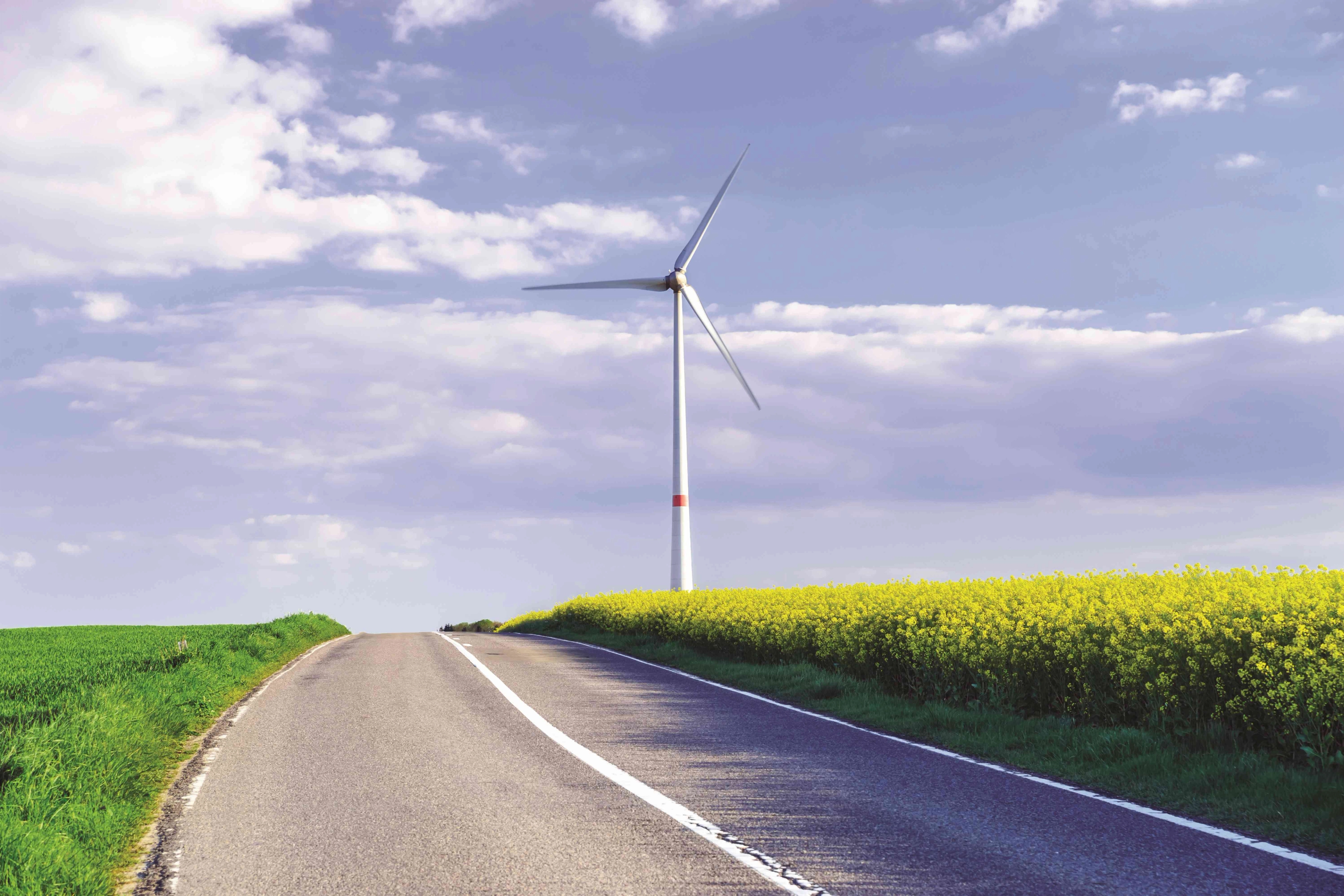 Luminus windturbine in een veld vlakbij een straat.