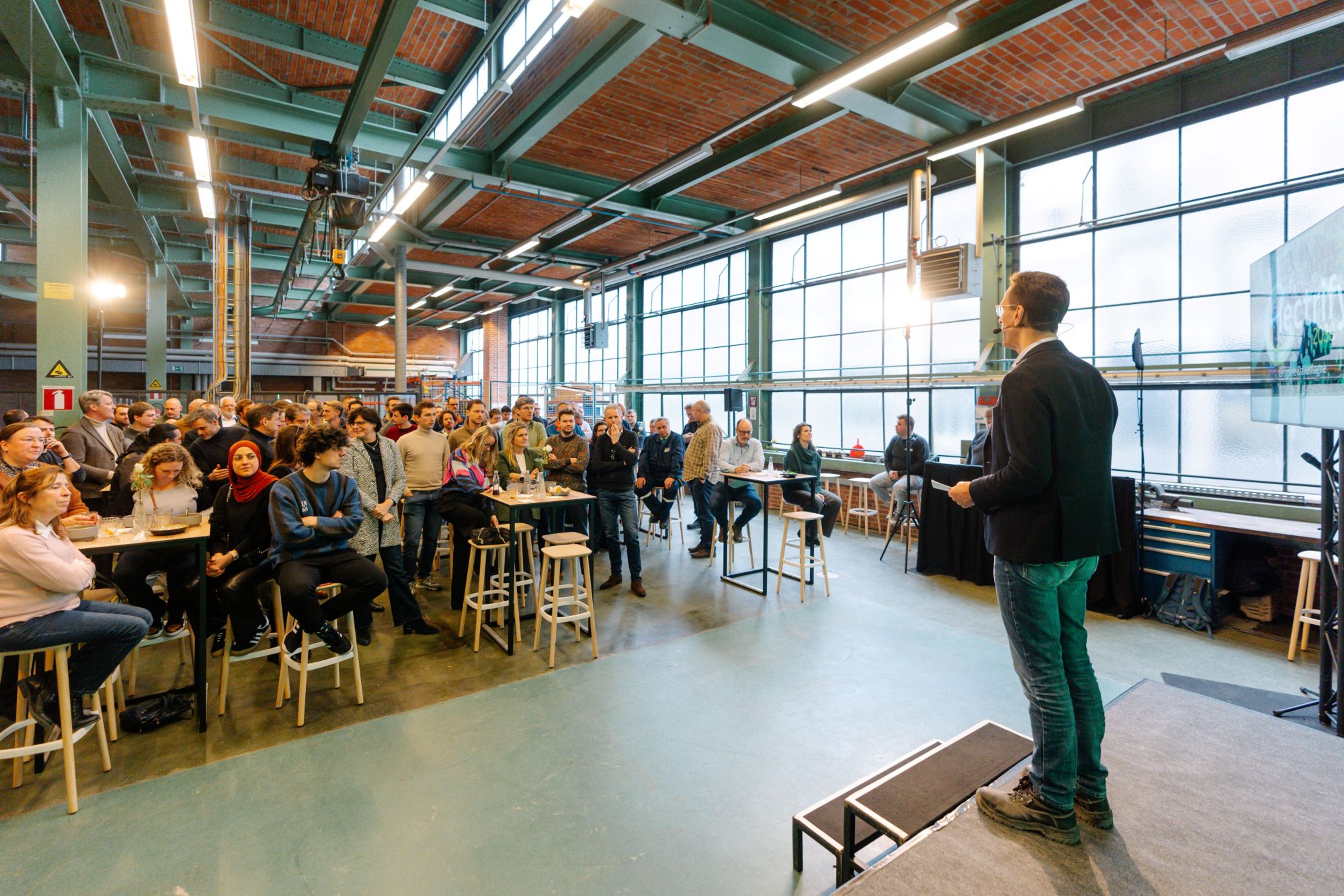Man spreekt toehoorders toe in een industrieel gebouw