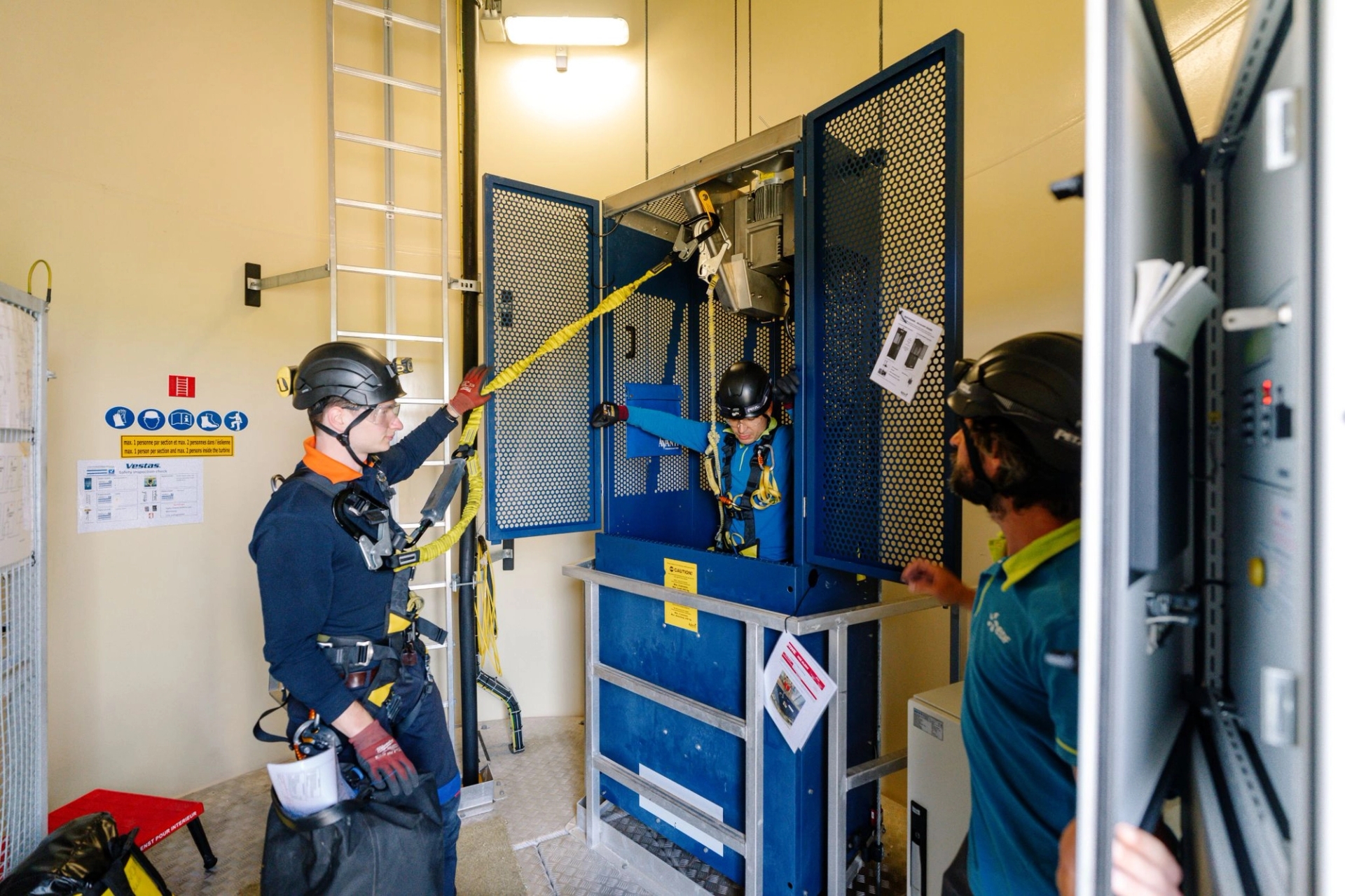 Trois techniciens inspectent les machines à l'intérieur d'une éolienne