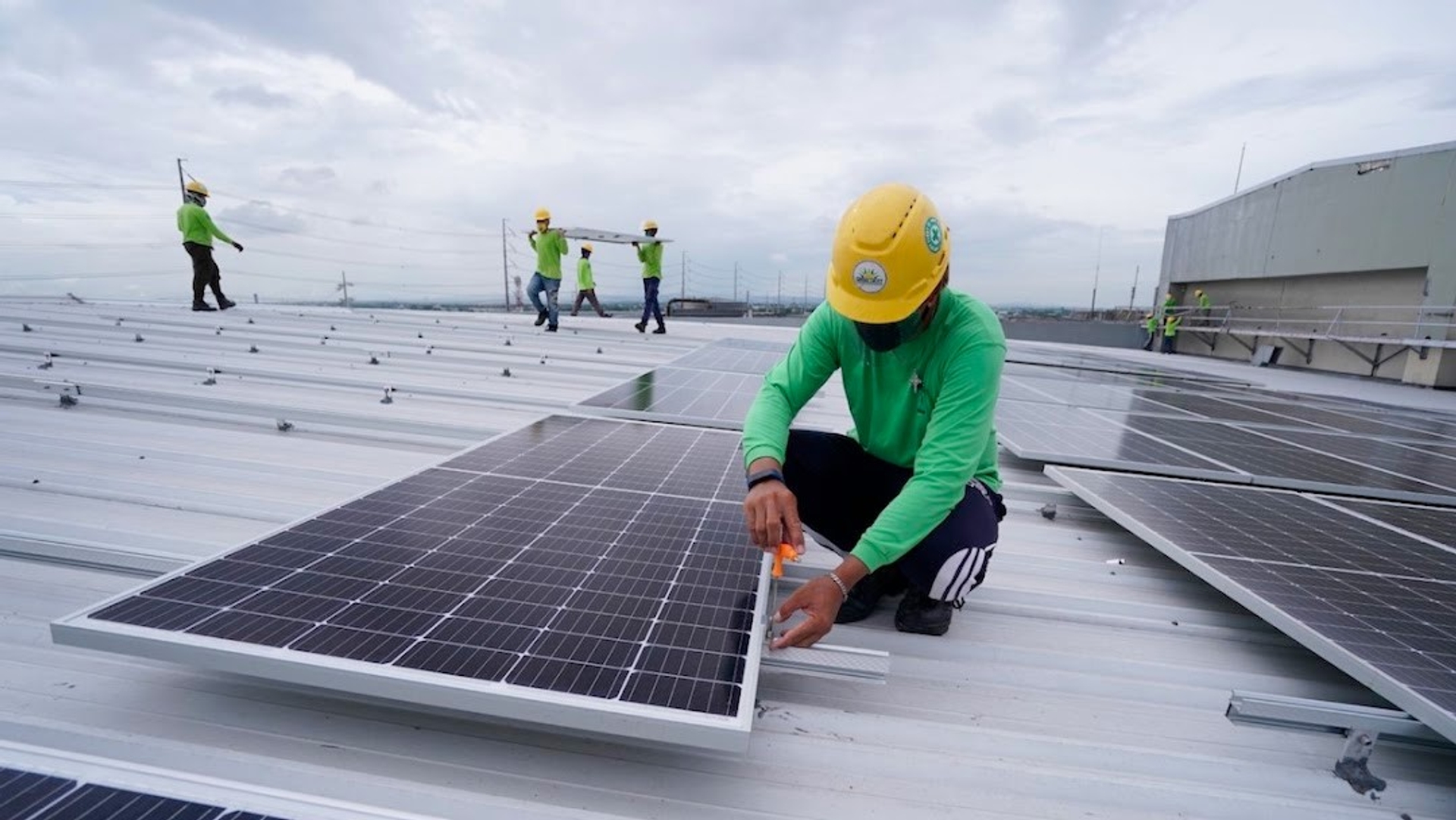 Techniciens installant des panneaux solaires sur le toit d’un bâtiment industriel, illustrant la transition vers une énergie propre et durable
