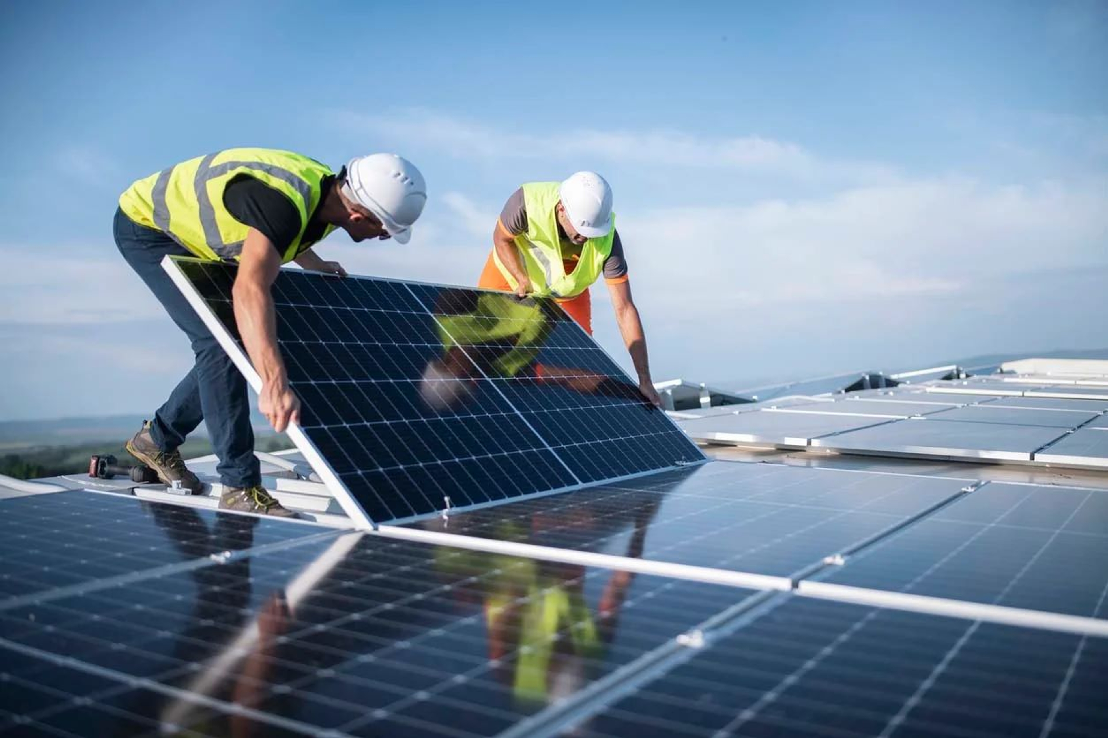2 hommes installent des panneaux solaires sur un toit plat