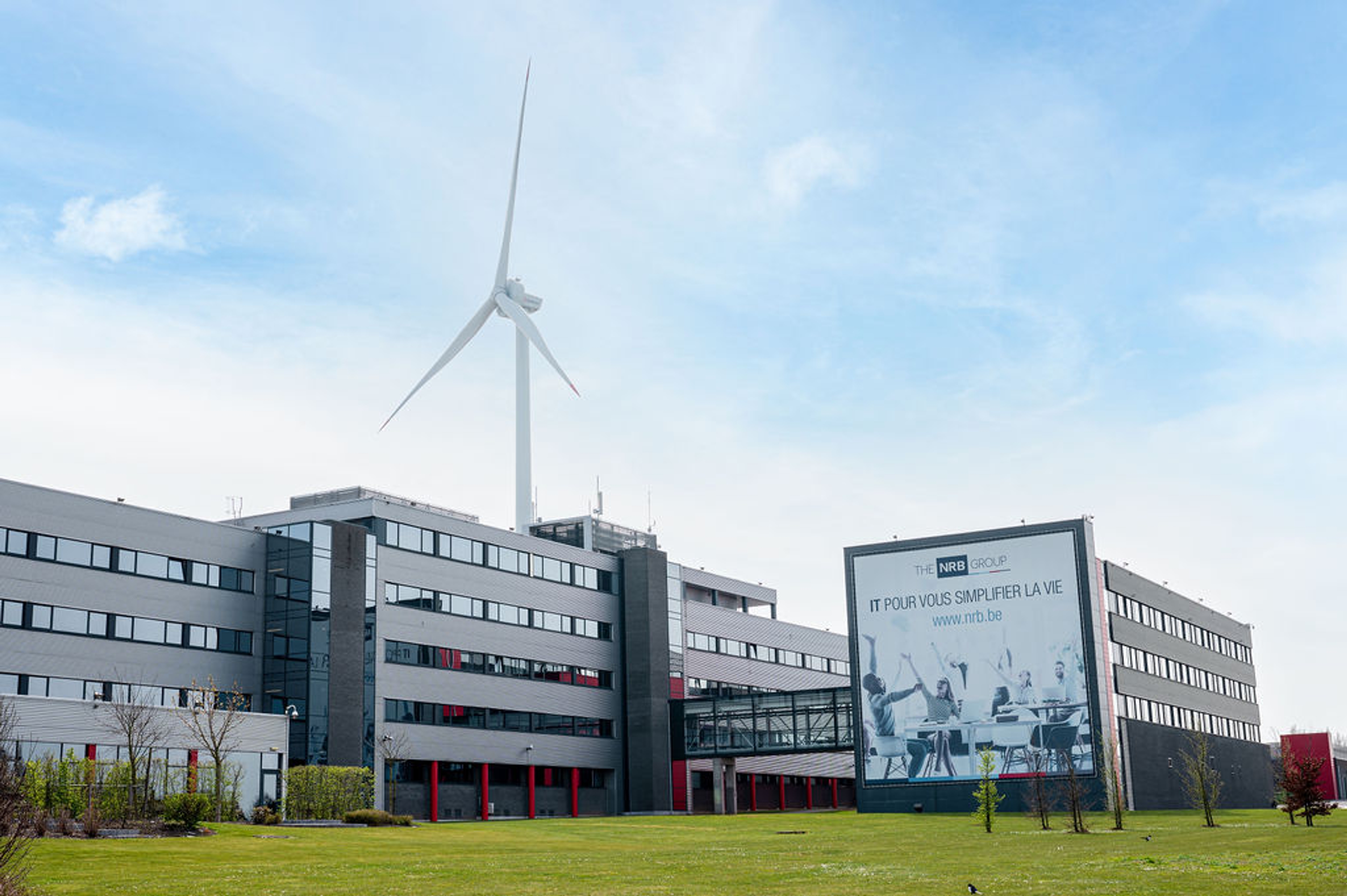 Kantoor Haut-Sart NRB-group met windturbine in achtergond.