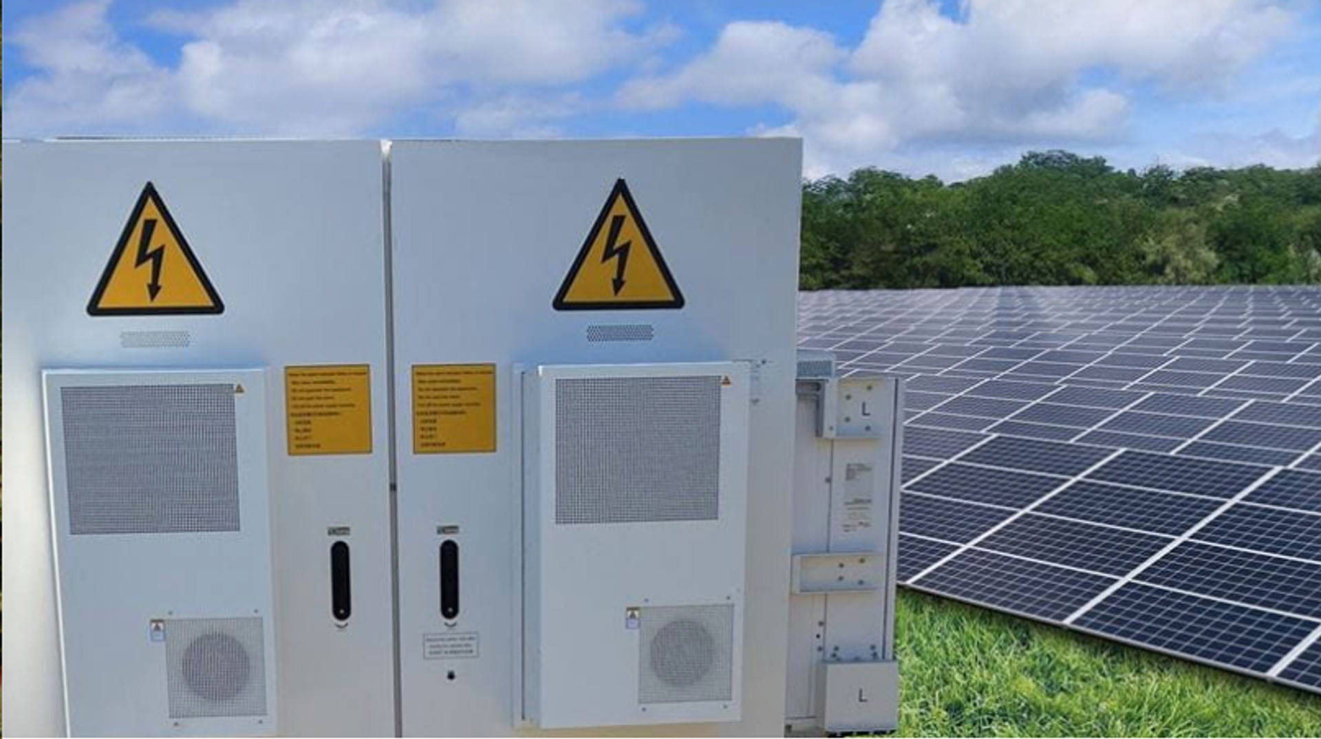 Armoires électriques haute tension situées à proximité d’un champ de panneaux solaires, sous un ciel partiellement nuageux.