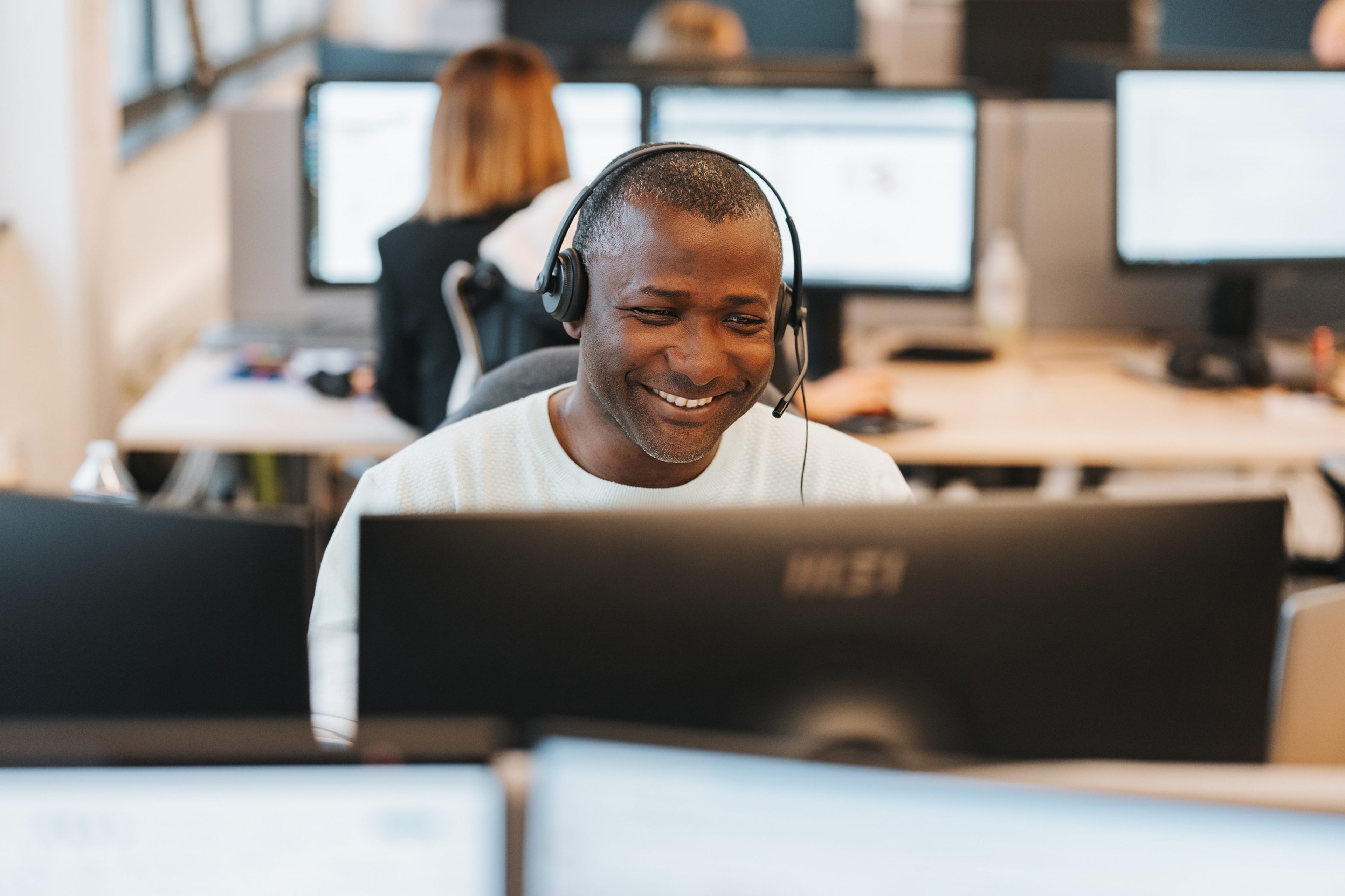 Femme assise dehors sur un muret en train de téléphoner avec son PC à côté d'elle