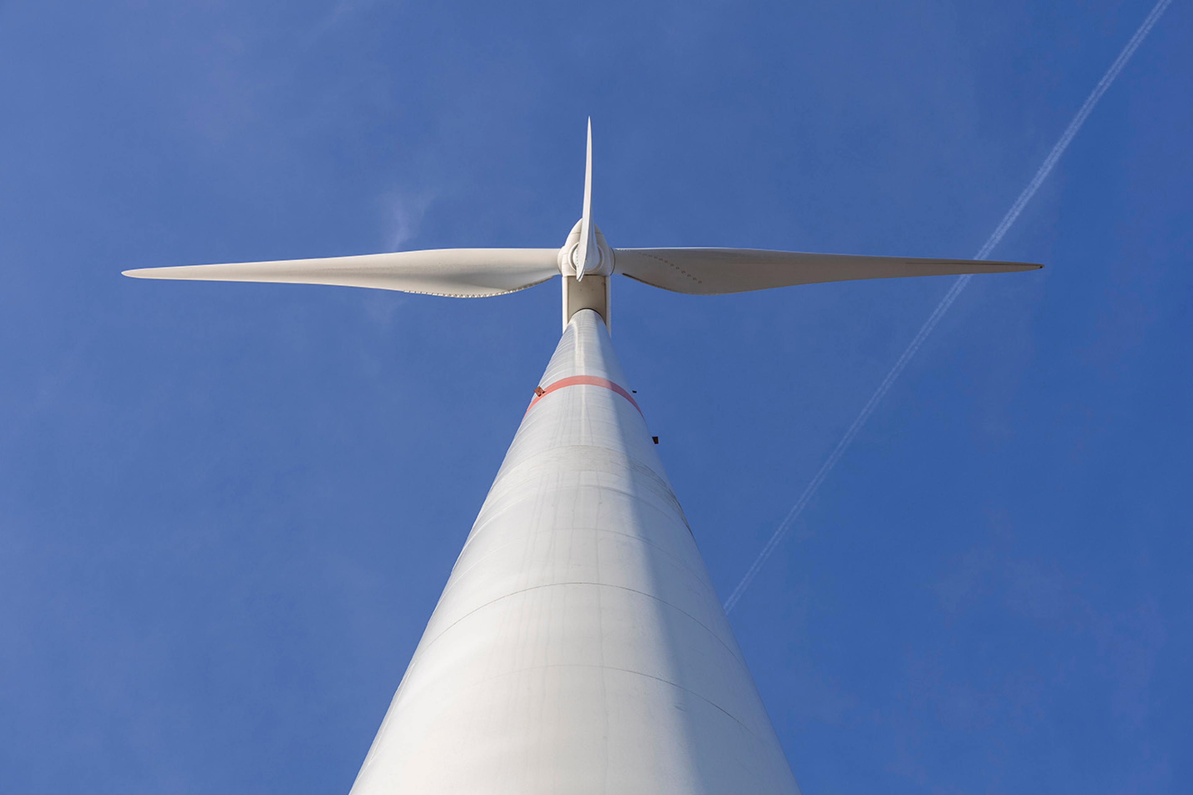 Windturbine gezien van onderen, tegen staalblauwe hemel.