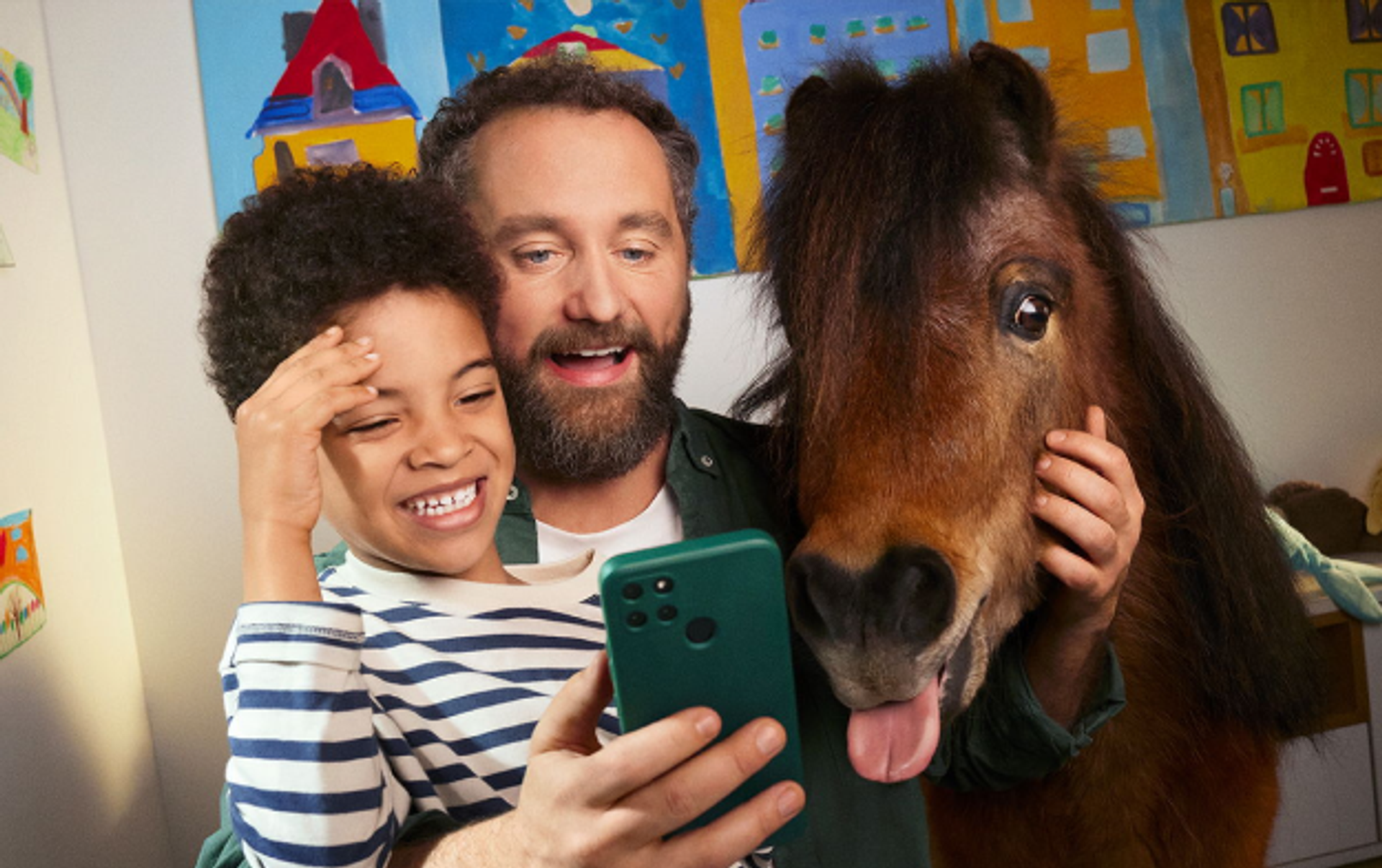 Man met kind en pony kijken op smartphone