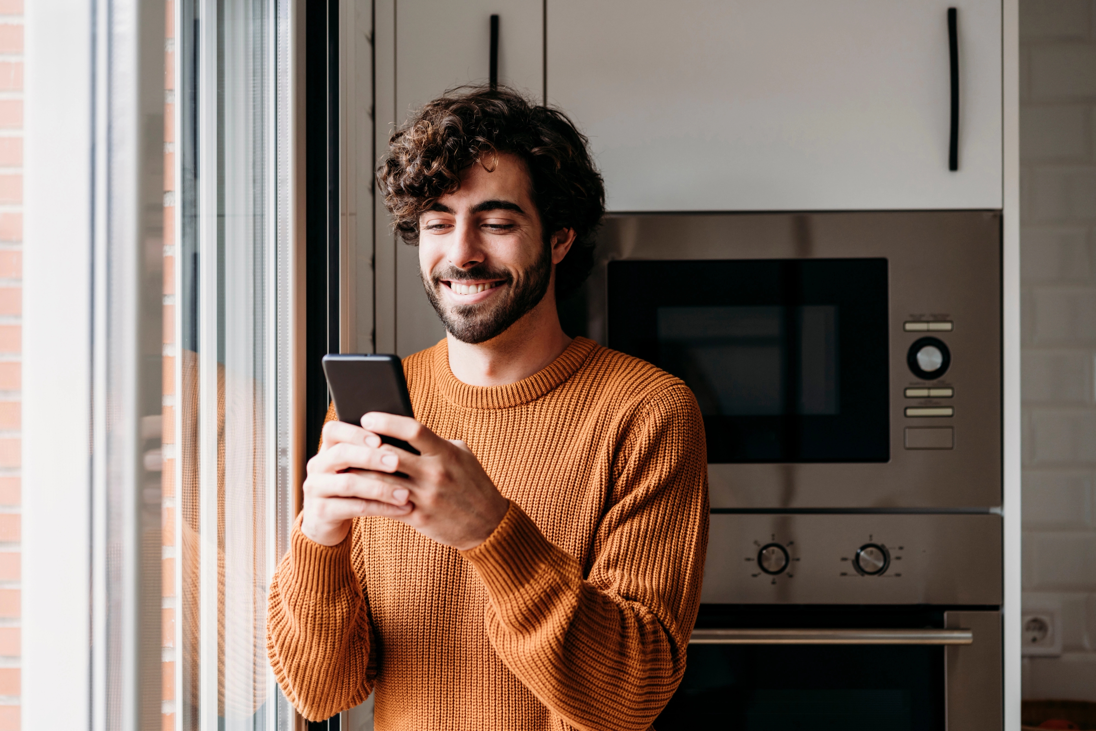 Homme souriante et écrivant sur son smartphone