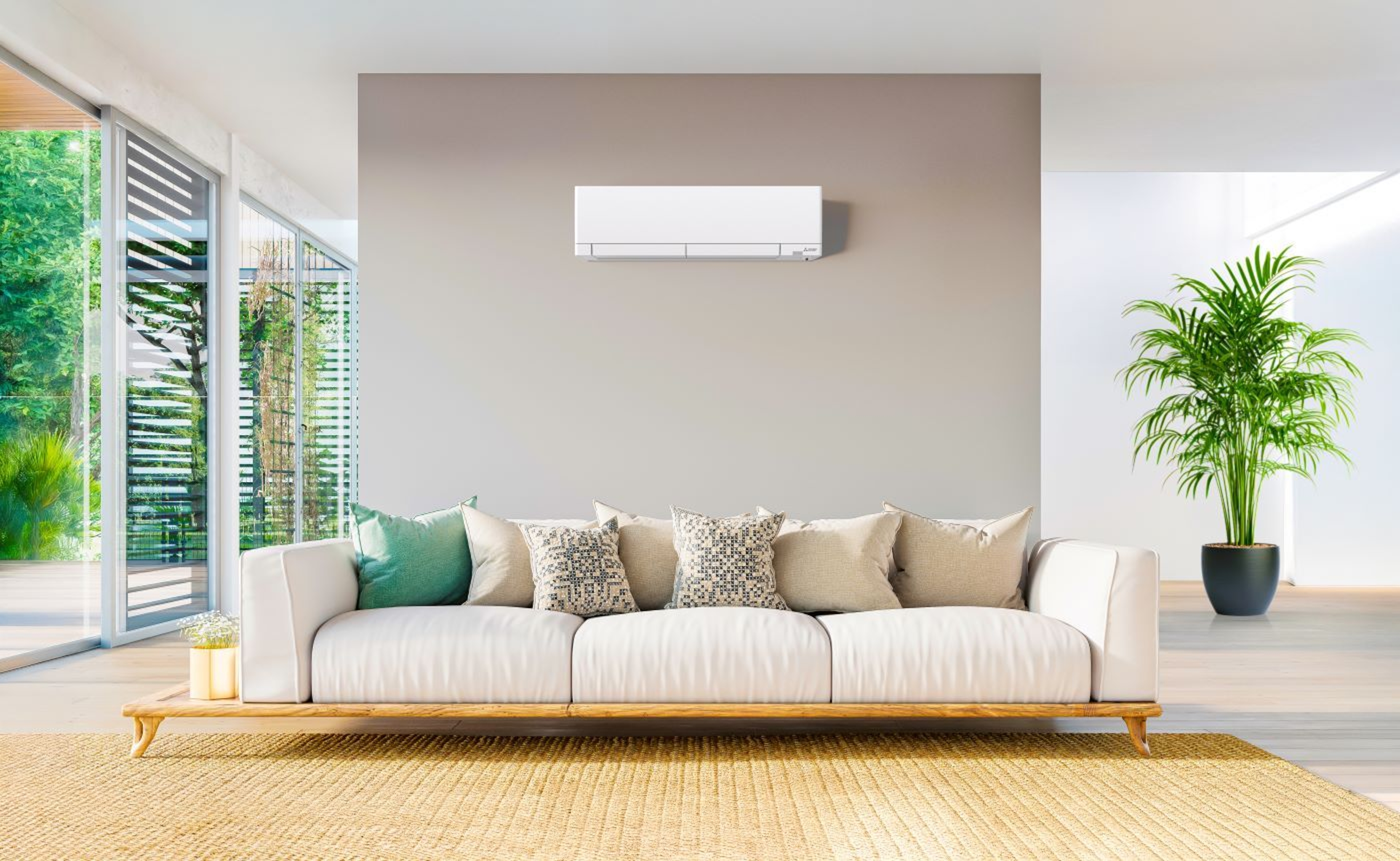 Lucht-lucht warmtepomp, binnenunit in een moderne living met grote zetel, ramen links en plant rechts.rmtepomp tegen een witte buitenmuur op een terras. 