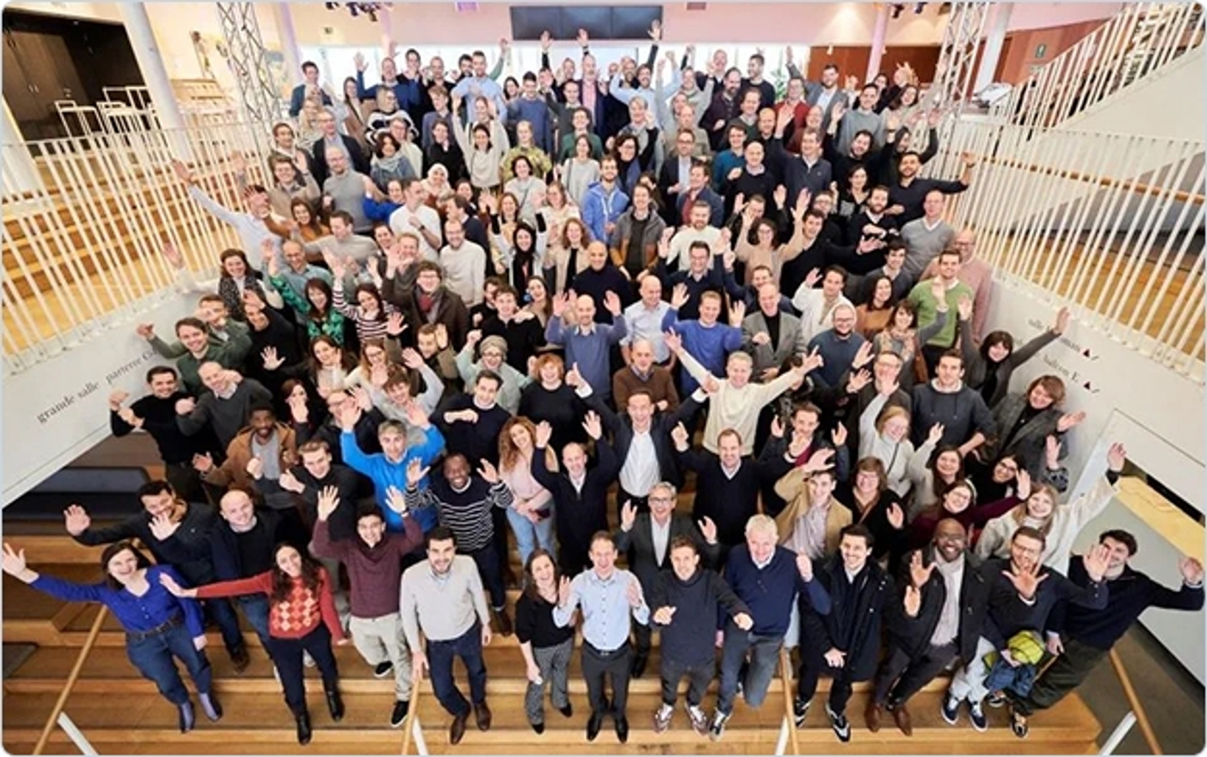 grote groep medewerkers in een auditorium, steken de handen in de lucht