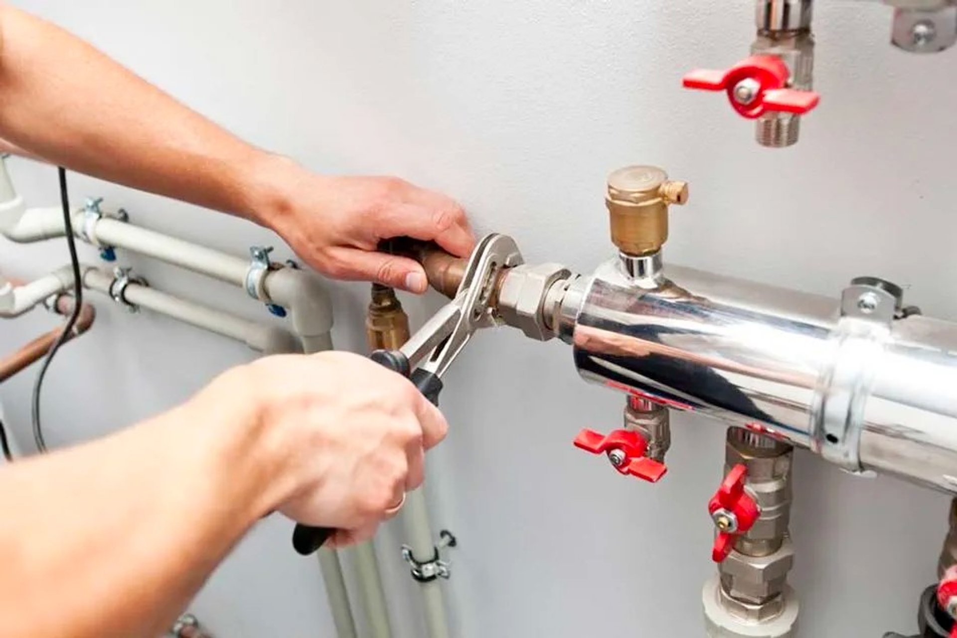Gros plan sur un technicien utilisant une clé pour régler des tuyaux et vannes d’une installation de chauffage