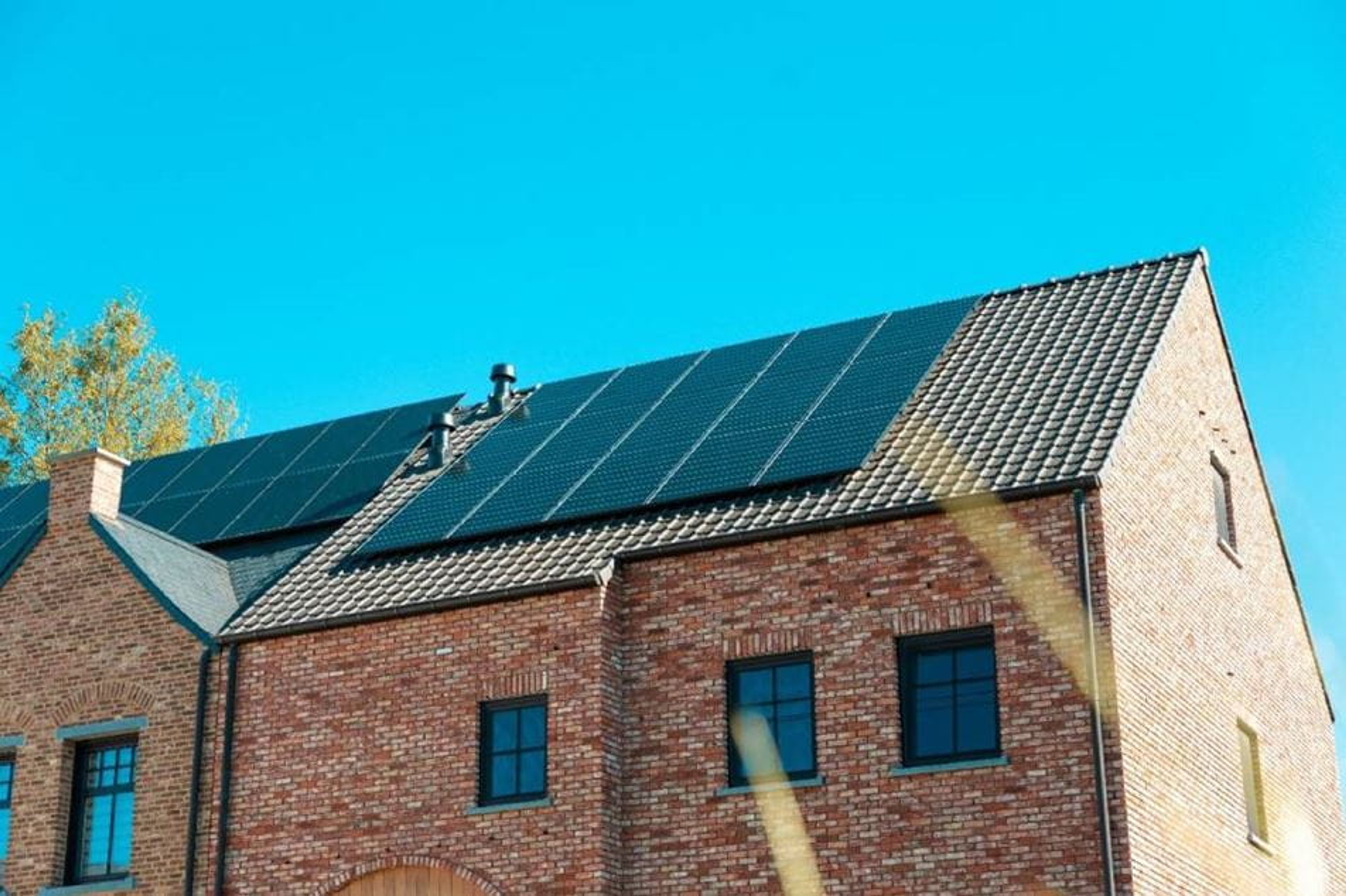 Maison en briques avec des panneaux solaires installés sur le toit sous un ciel bleu clair