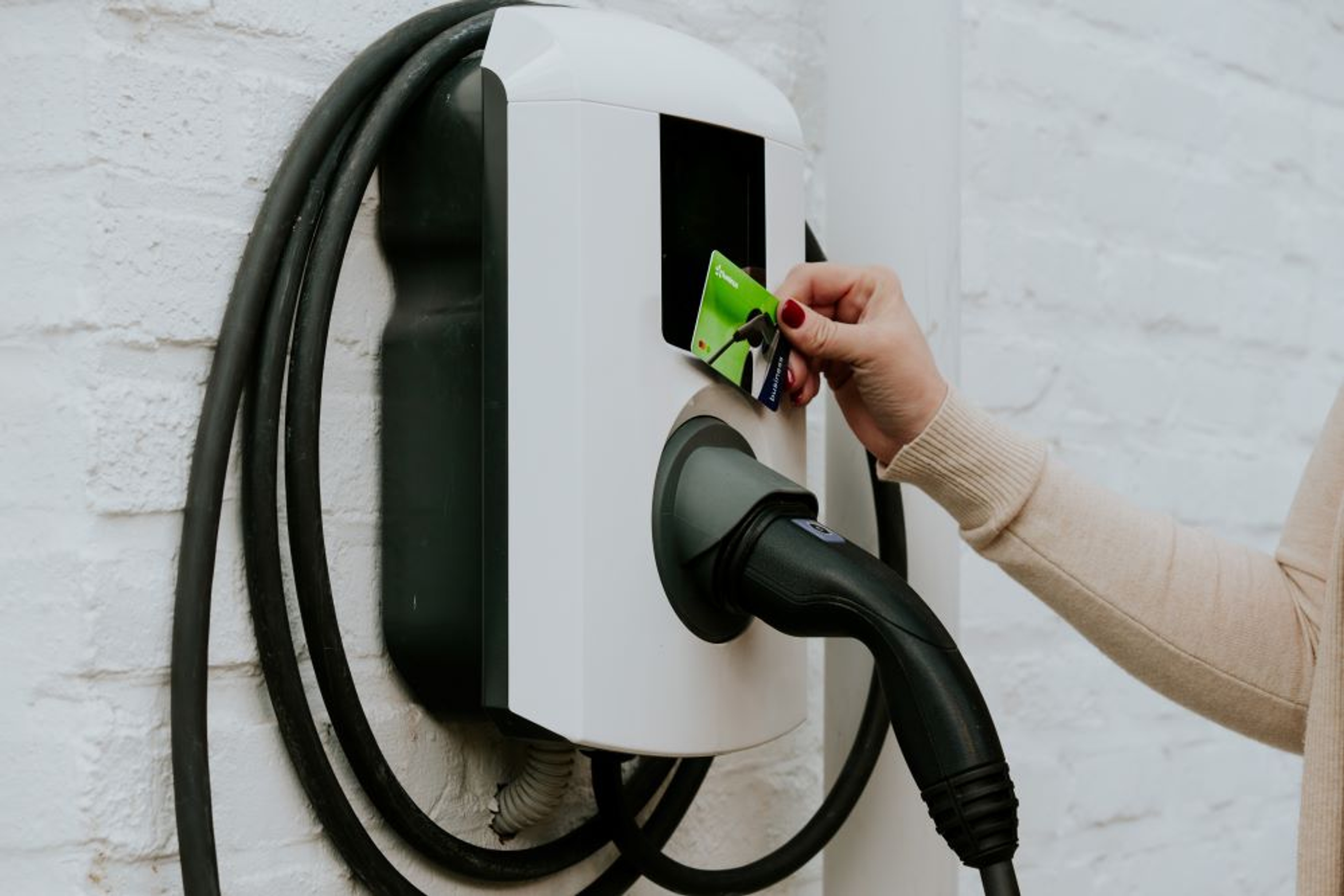 Une dame passe son badge de recharge devant une borne de recharge Alfen Eve