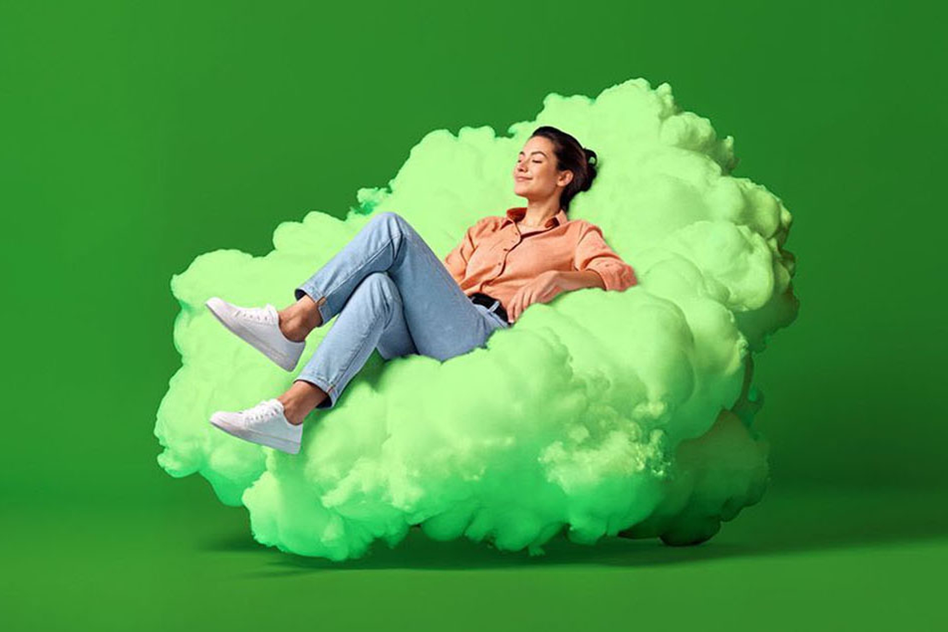 Jonge vrouw ligt zalig op een lichtgroene wolk