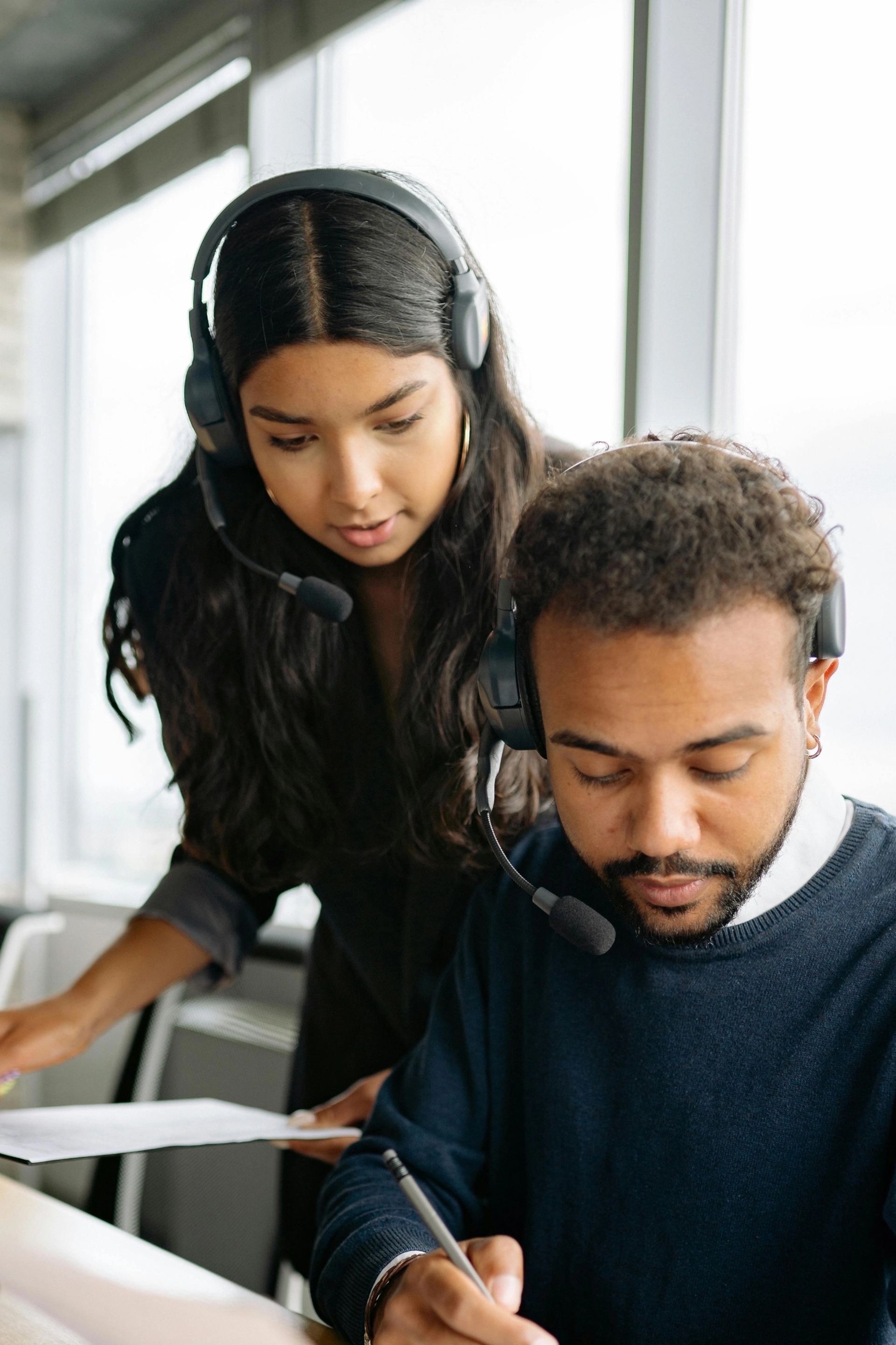 2 service agents aan een bureau met toetsenbord buigen zich over een dossier.