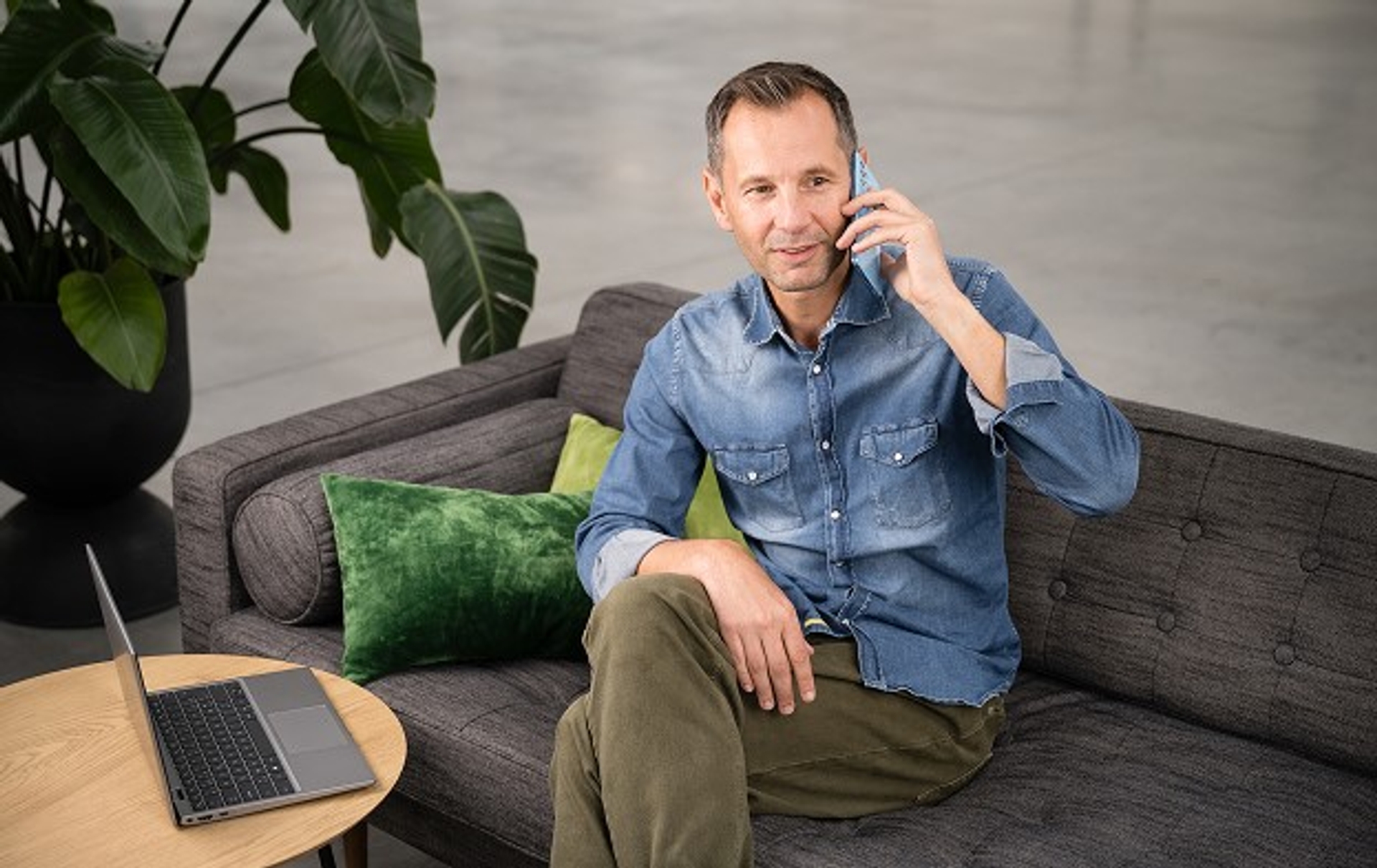 Homme au téléphone dans un fauteuil avec son ordinateur devant lui