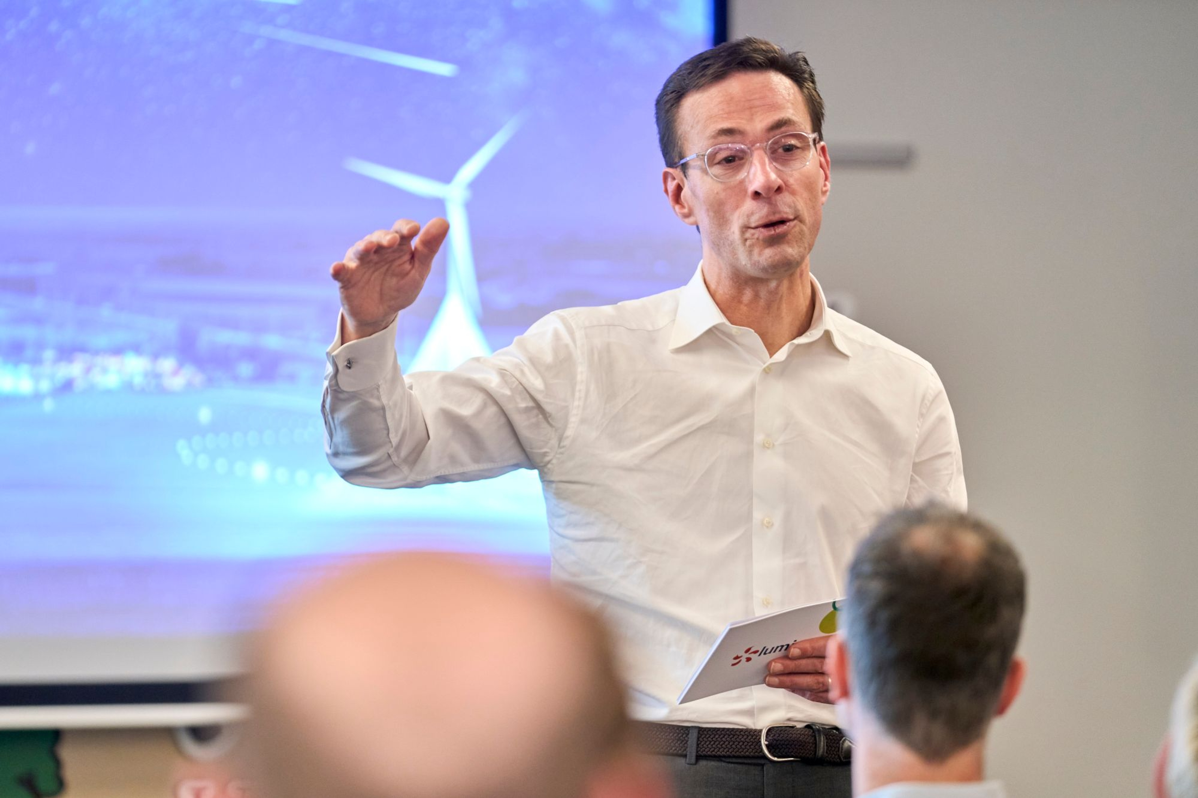 CEO Grégoire Dallemagne geeft een lezing, projectiescherm op de achtergrond