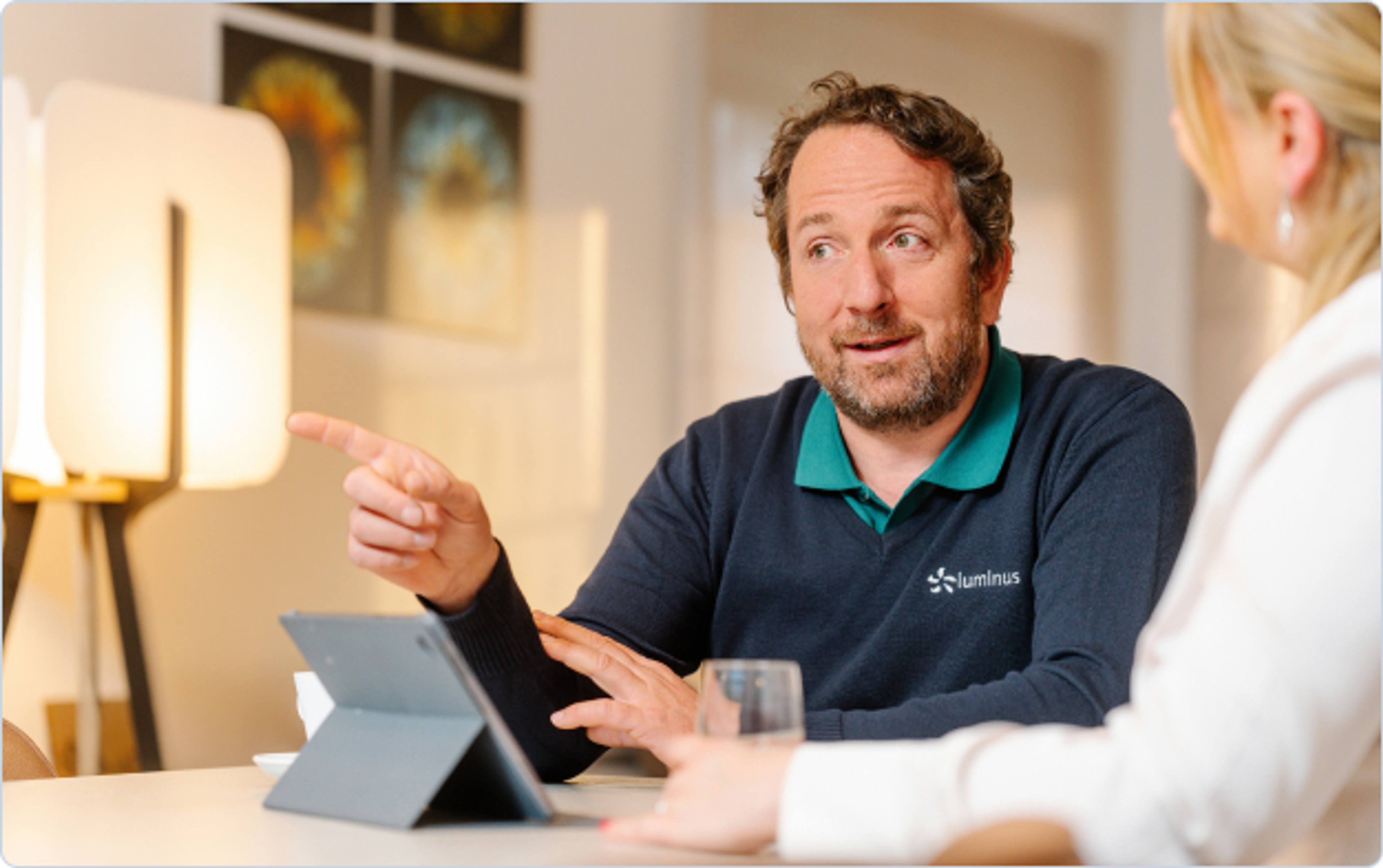Collaborateur Luminus qui discute avec une cliente, attablés devant une tablette
