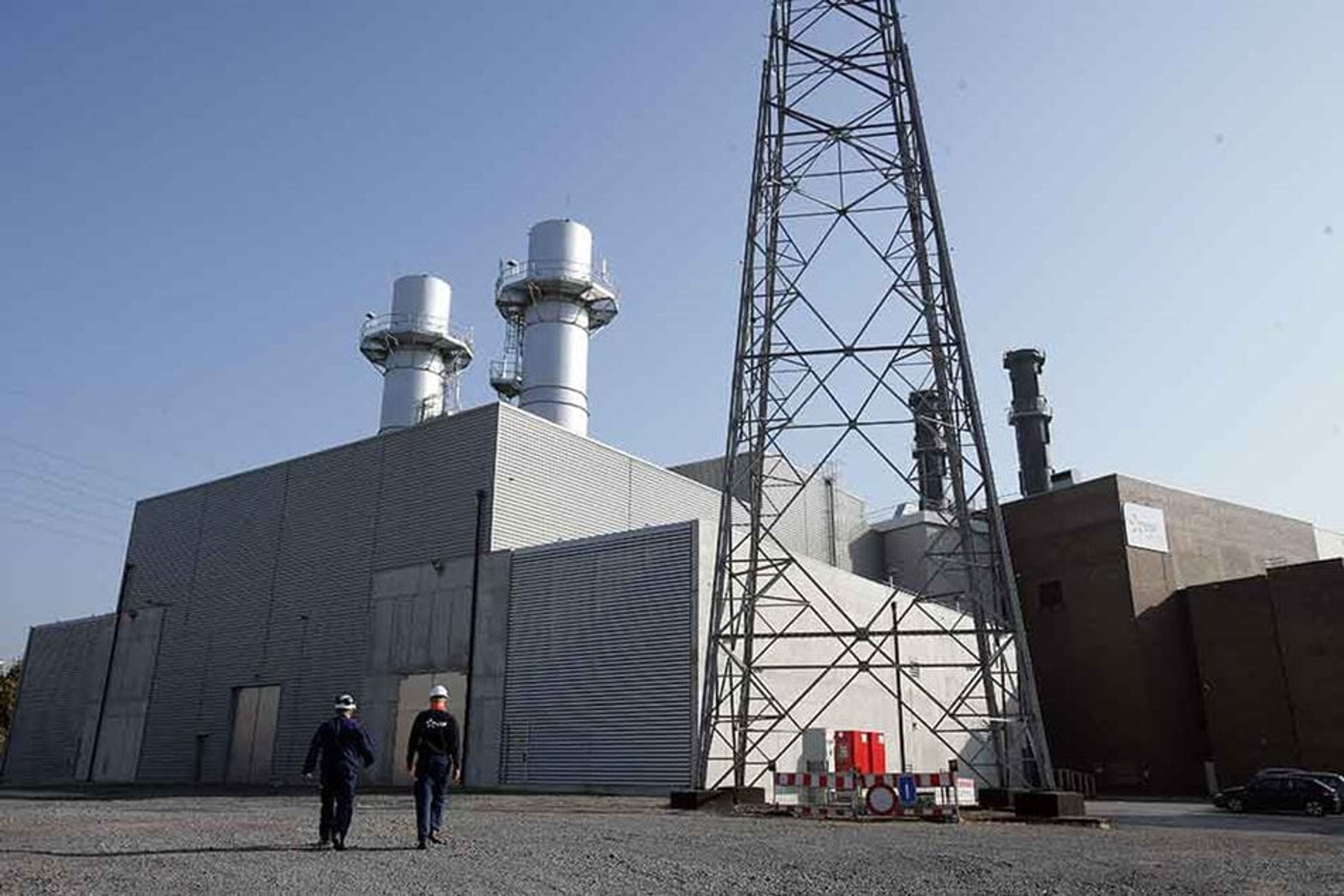 Thermische centrale van Luminus, 2 technici met helm wandelen op ons toe.