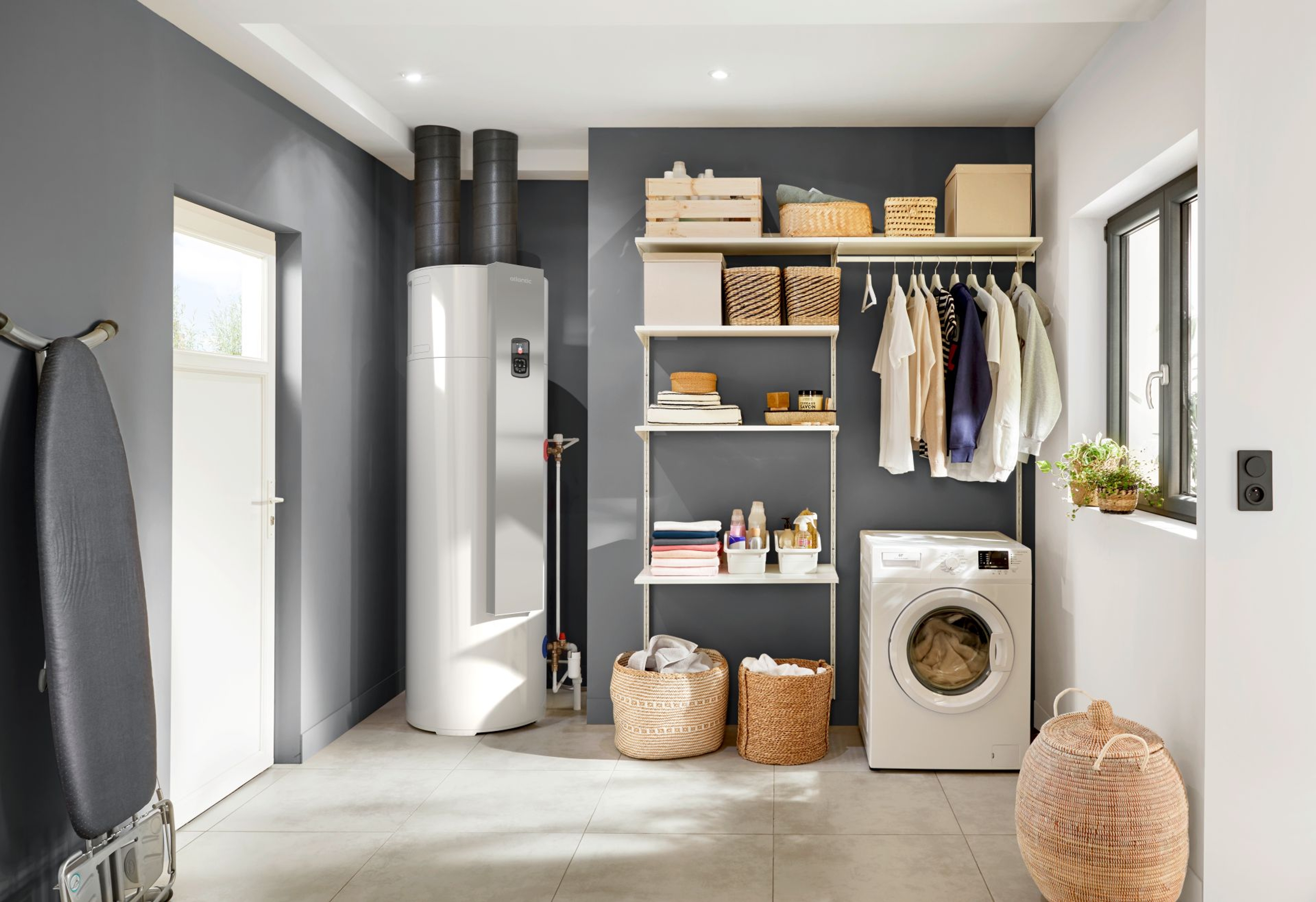 Boiler thermodynamique installé dans une buanderie à côté d'un meuble avec des serviettes