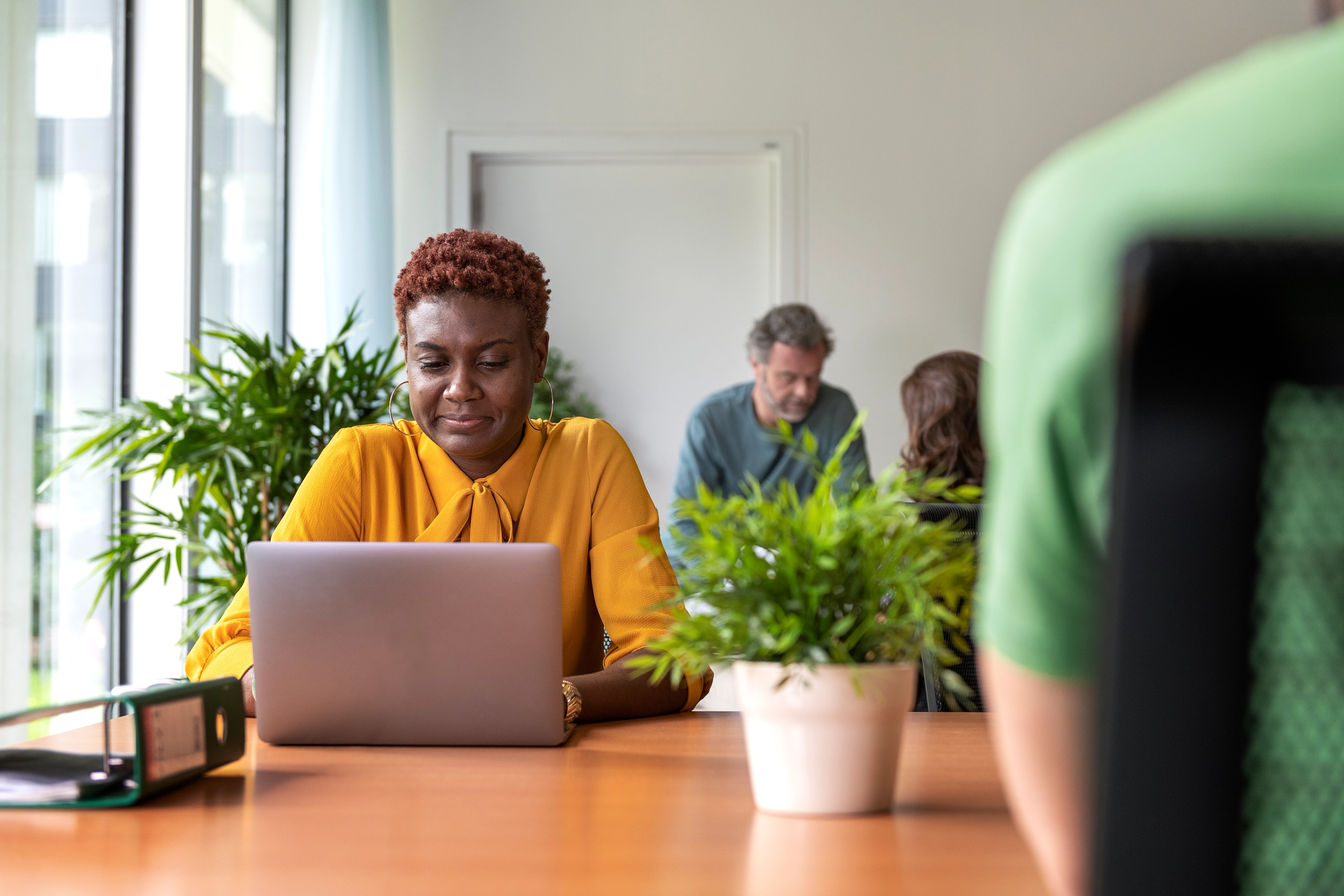 Lady with yellow top working on her laptop at the office.