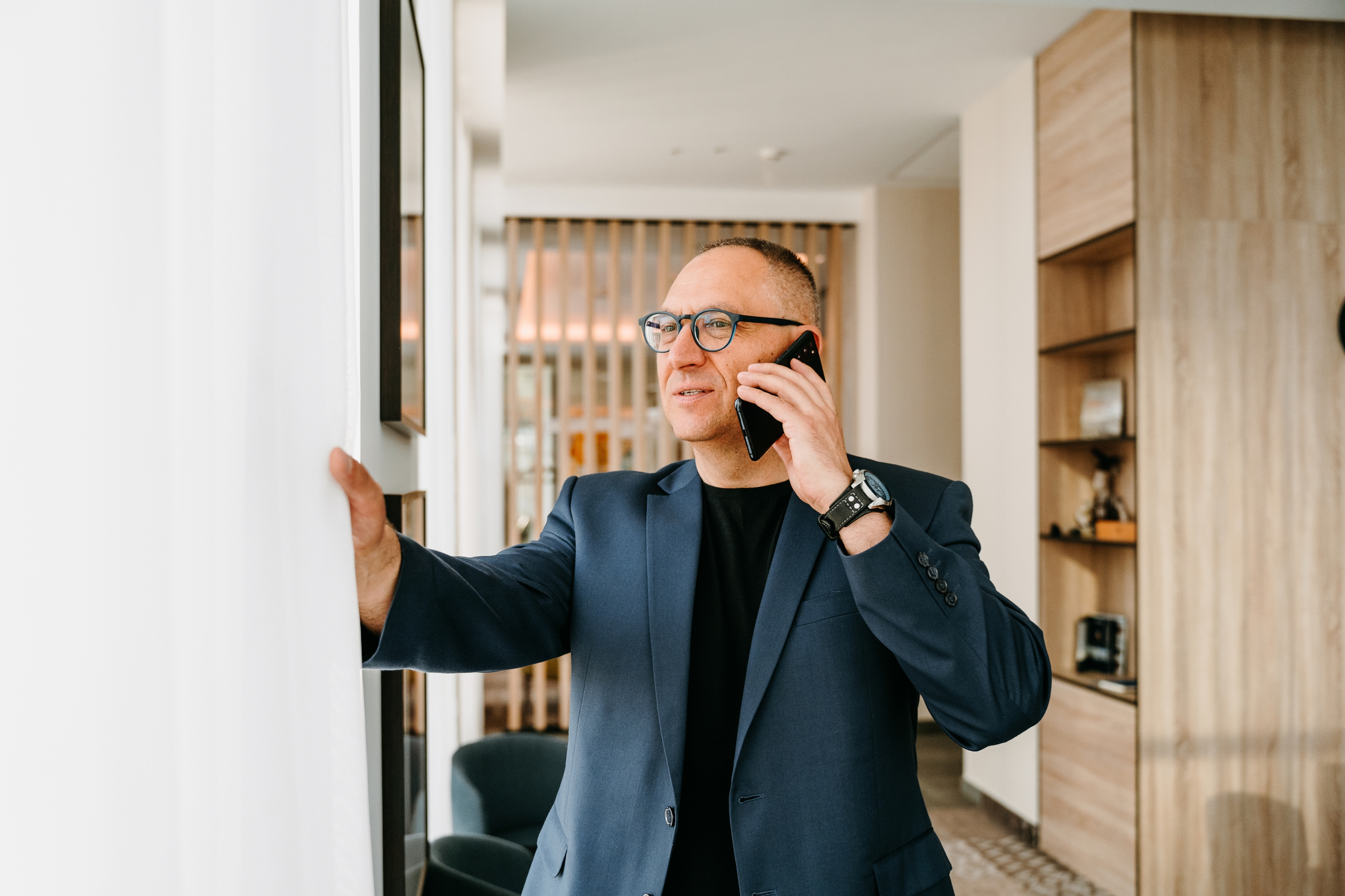 Homme debout dans un bureau lumineux, parlant au téléphone près d'une fenêtre