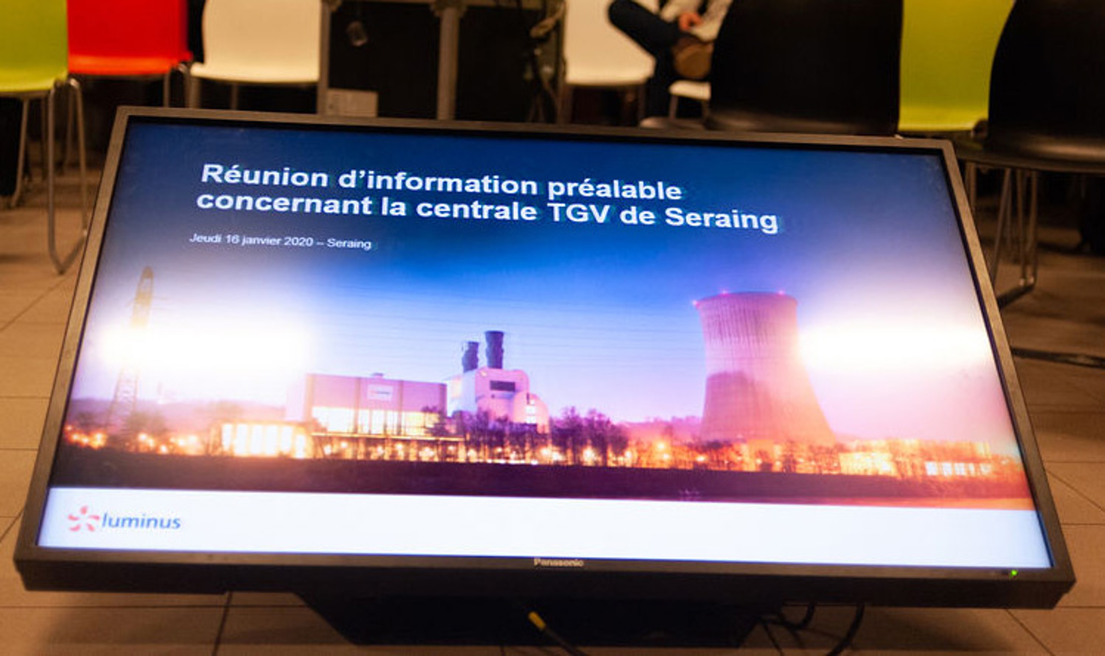 Femme assise dehors sur un muret en train de téléphoner avec son PC à côté d'elle