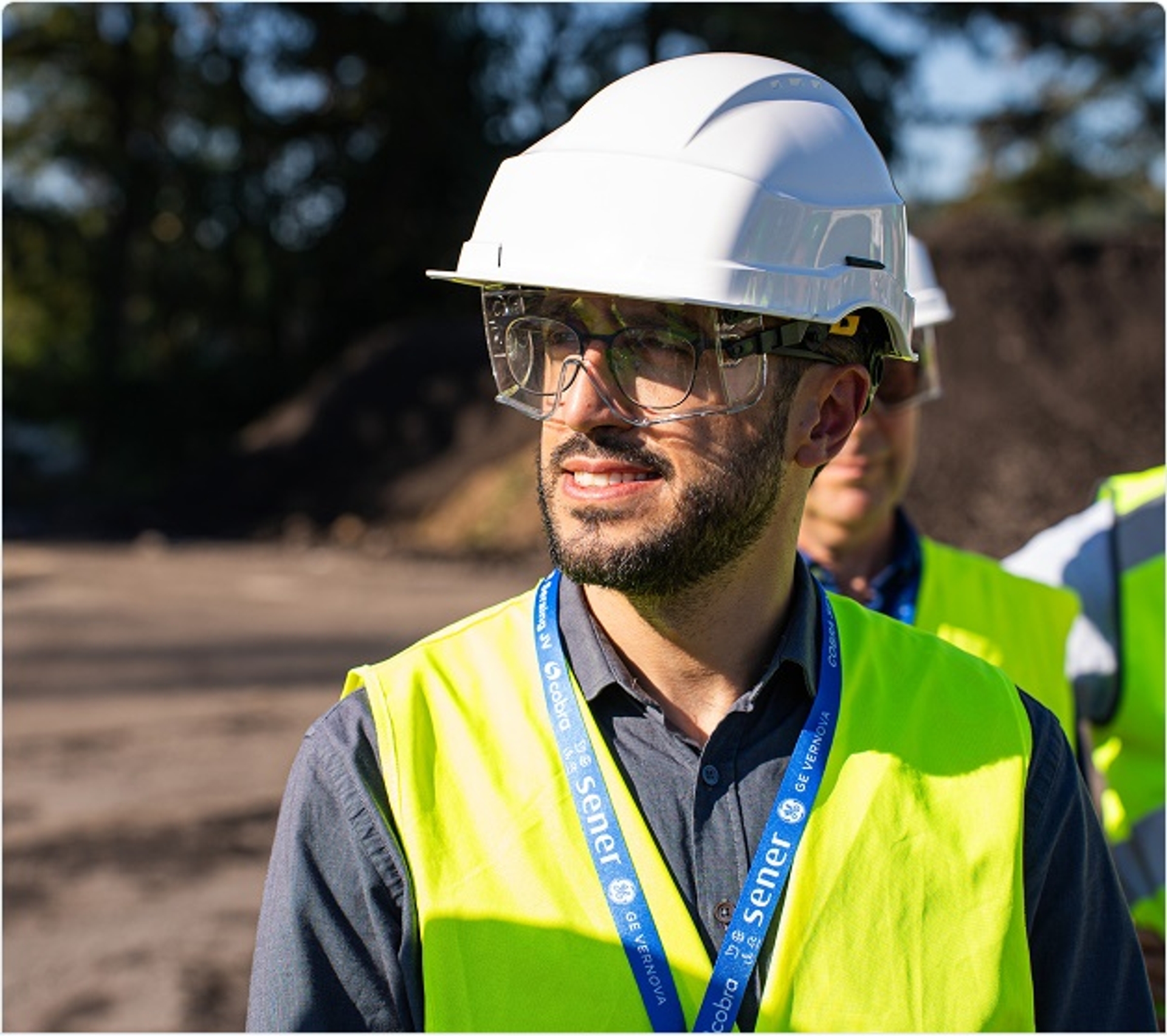 Man met witte helm, veiligheidsbril en geel hesje