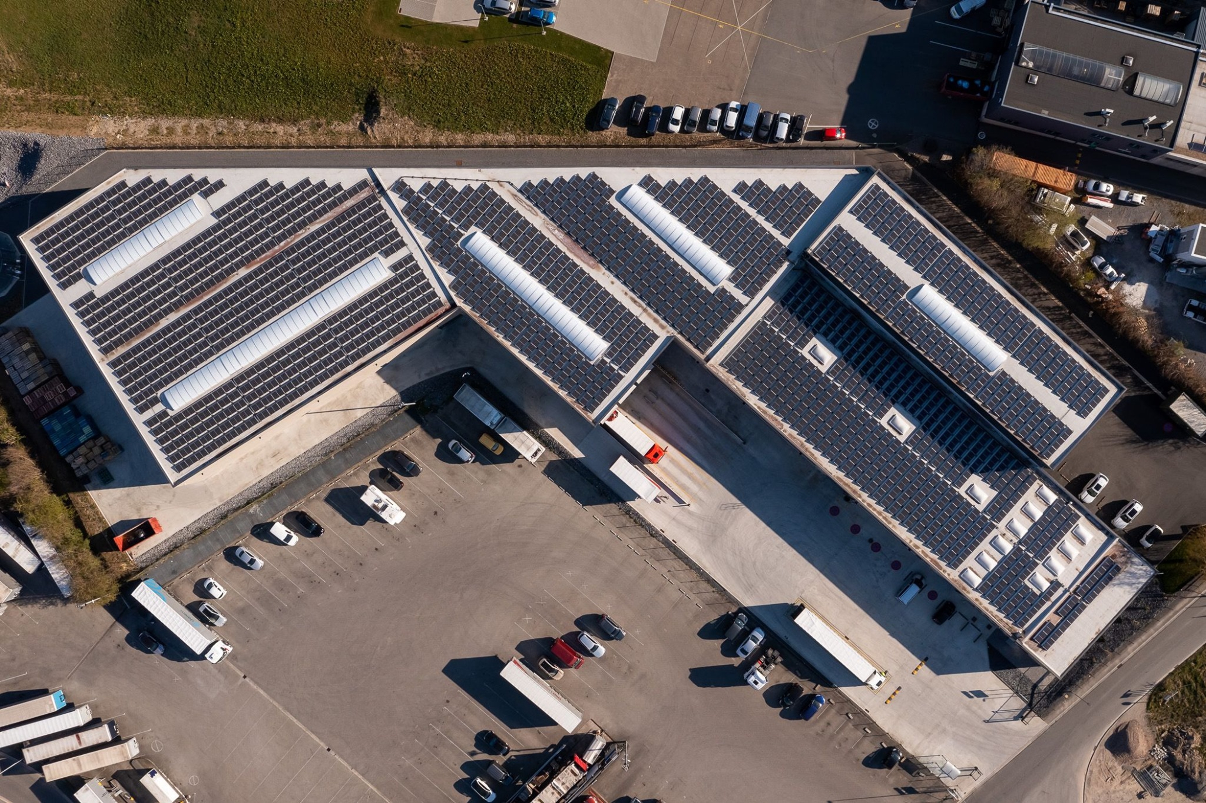 Vue aérienne d’un grand bâtiment industriel équipé de panneaux solaires sur le toit