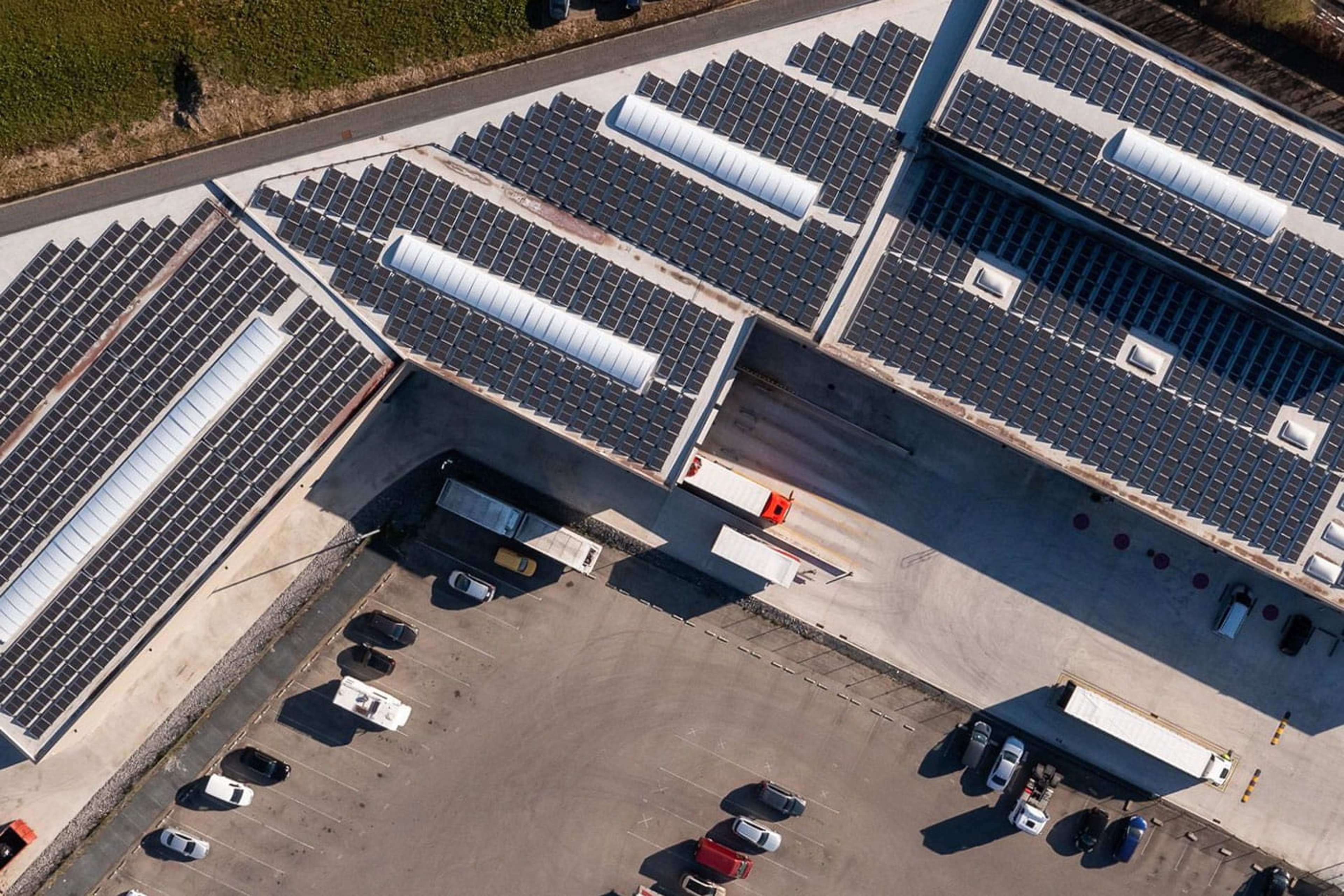 Vue aérienne d’un bâtiment industriel équipé de panneaux solaires sur les toits, illustrant une installation photovoltaïque réalisée par Luminus