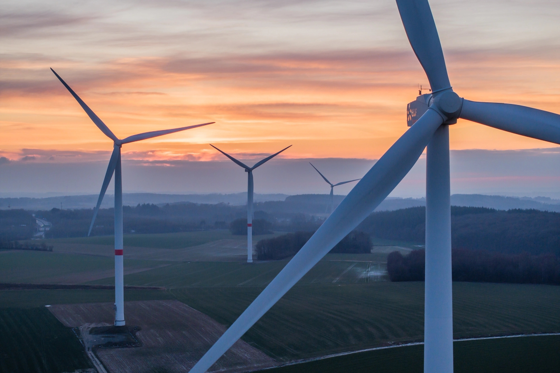Quatre éoliennes dans un champ au coucher du soleil