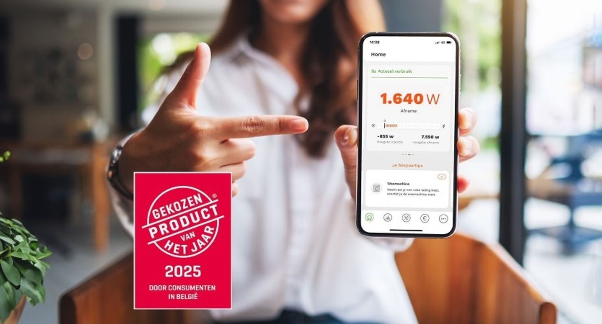Vrouw flou op de achtergond houdt smartphone vast en toont scherm van Energy Control Monitor, Gekozen product van het jaar 2025