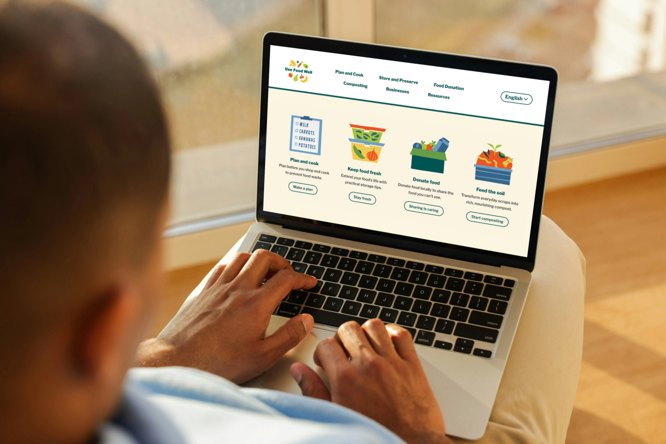 Person browsing the Use Food Well website resources page on a laptop, showing illustrated food storage guides