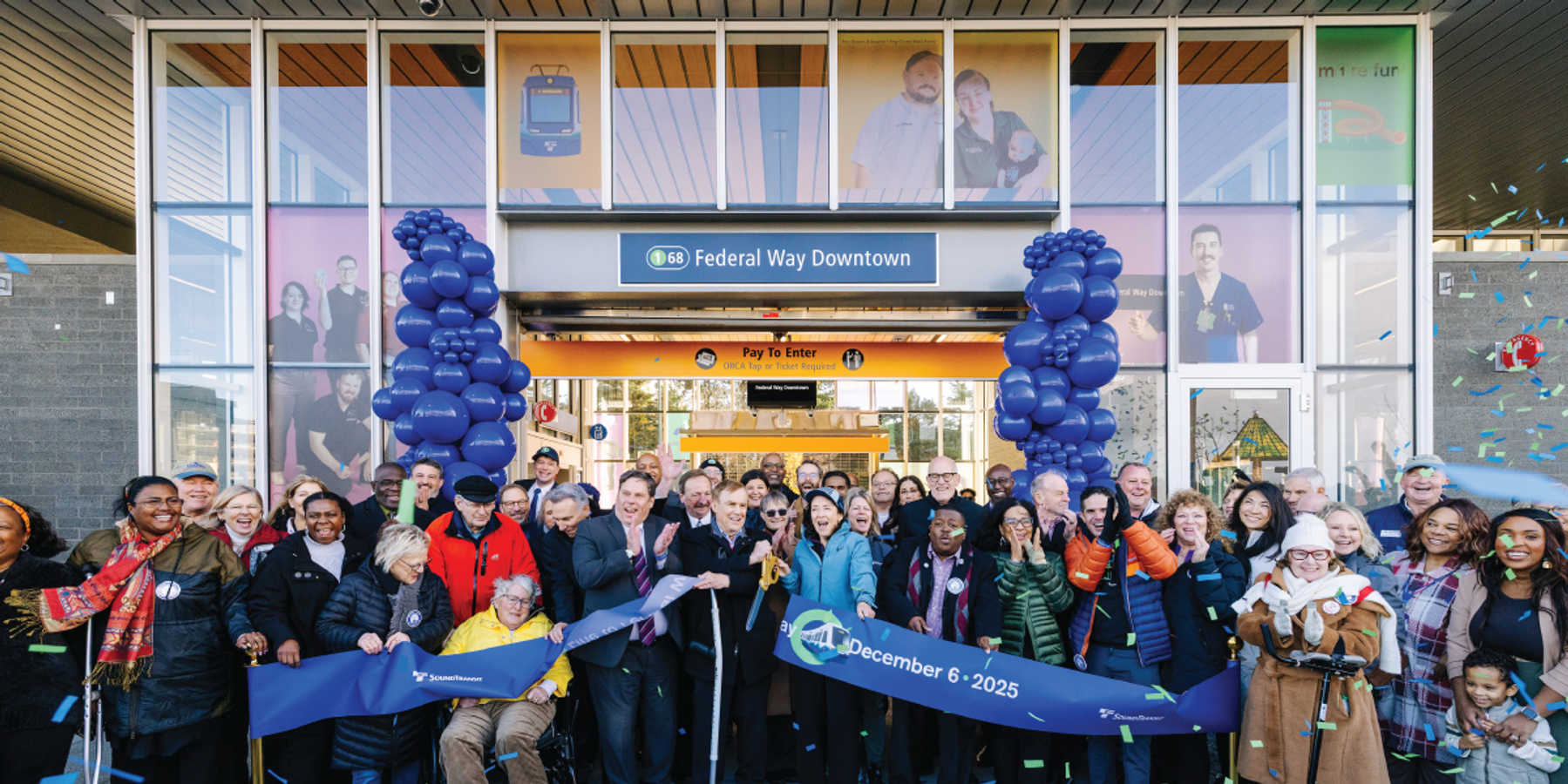 Ribbon-cutting ceremony at Federal Way Downtown Sound Transit station with a large group of community members, blue balloons, and confetti