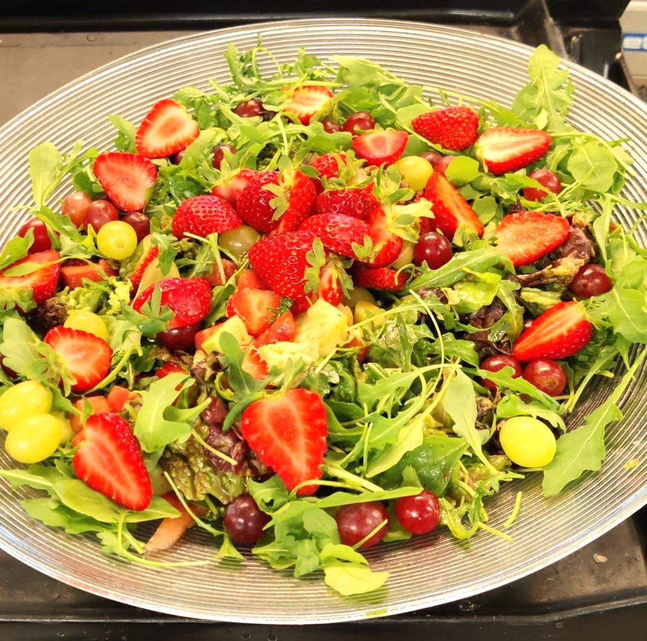 Strawberry, grape and arugula salad in a glass bowl