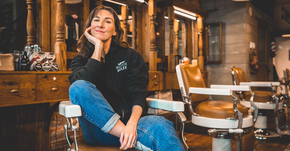 Woman smiles from her seat in a barber's chair