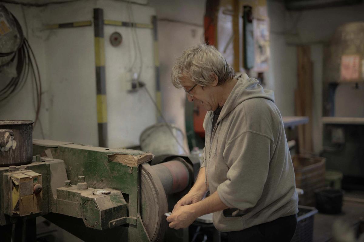 Older man using a grinding tool in a workshop