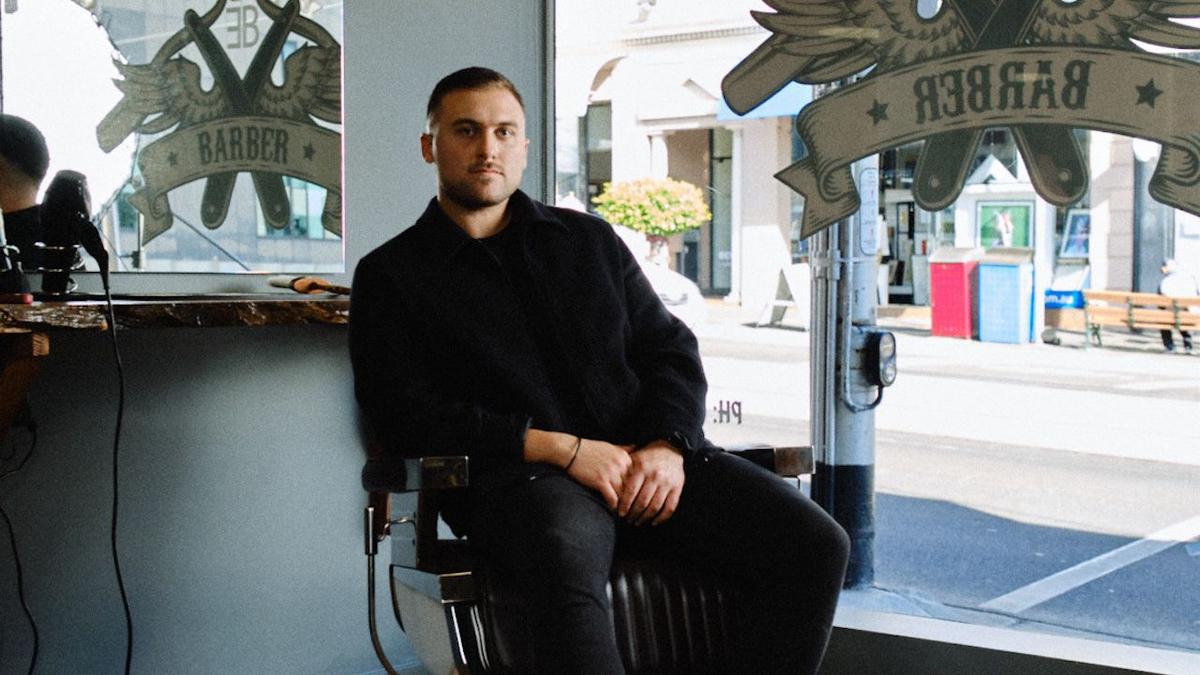 Seated young man looking to camera in a barber chair.