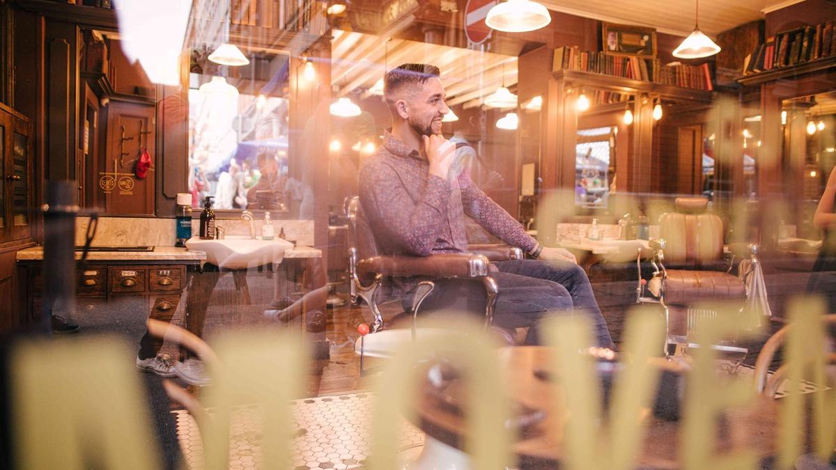 Man sitting in barber shop viewed through window