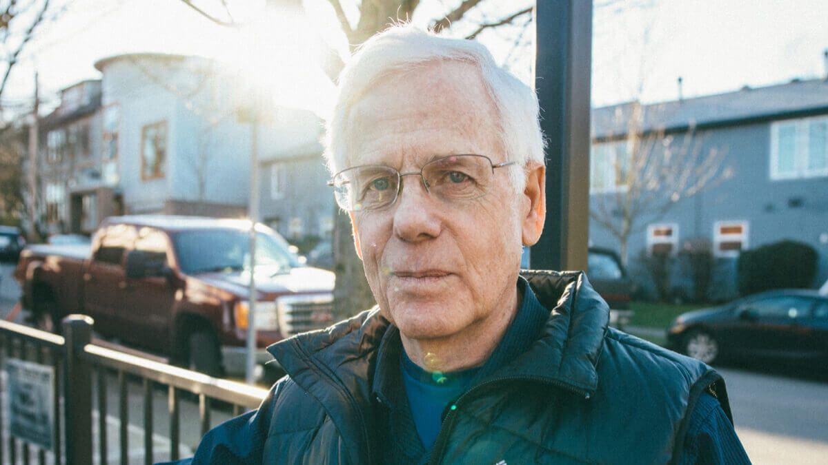 Older man standing alone on the sidewalk