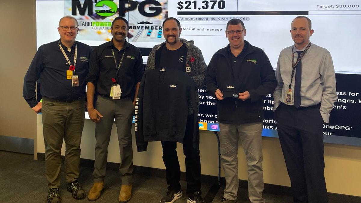 5 men stand in front of a fundraising page showing they've raised over $20,000