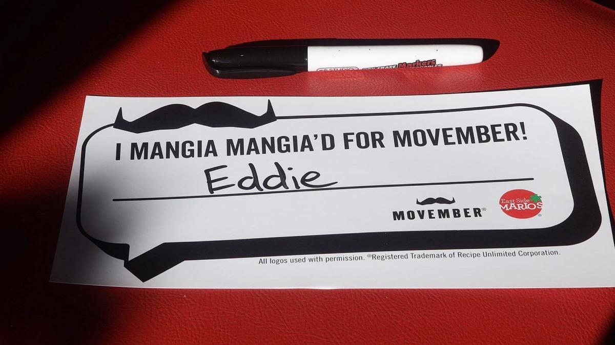 "I mangia mangiaed for Movember" appears on a piece of paper on a red restaurant booth chair